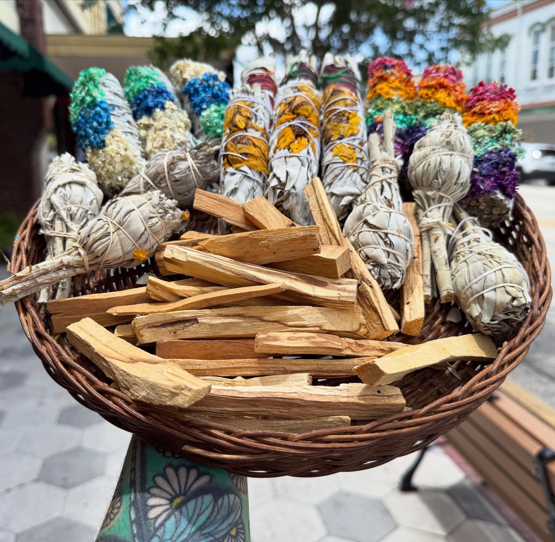 Basket of dried herbs and wooden sticks in colorful bundles at an outdoor market