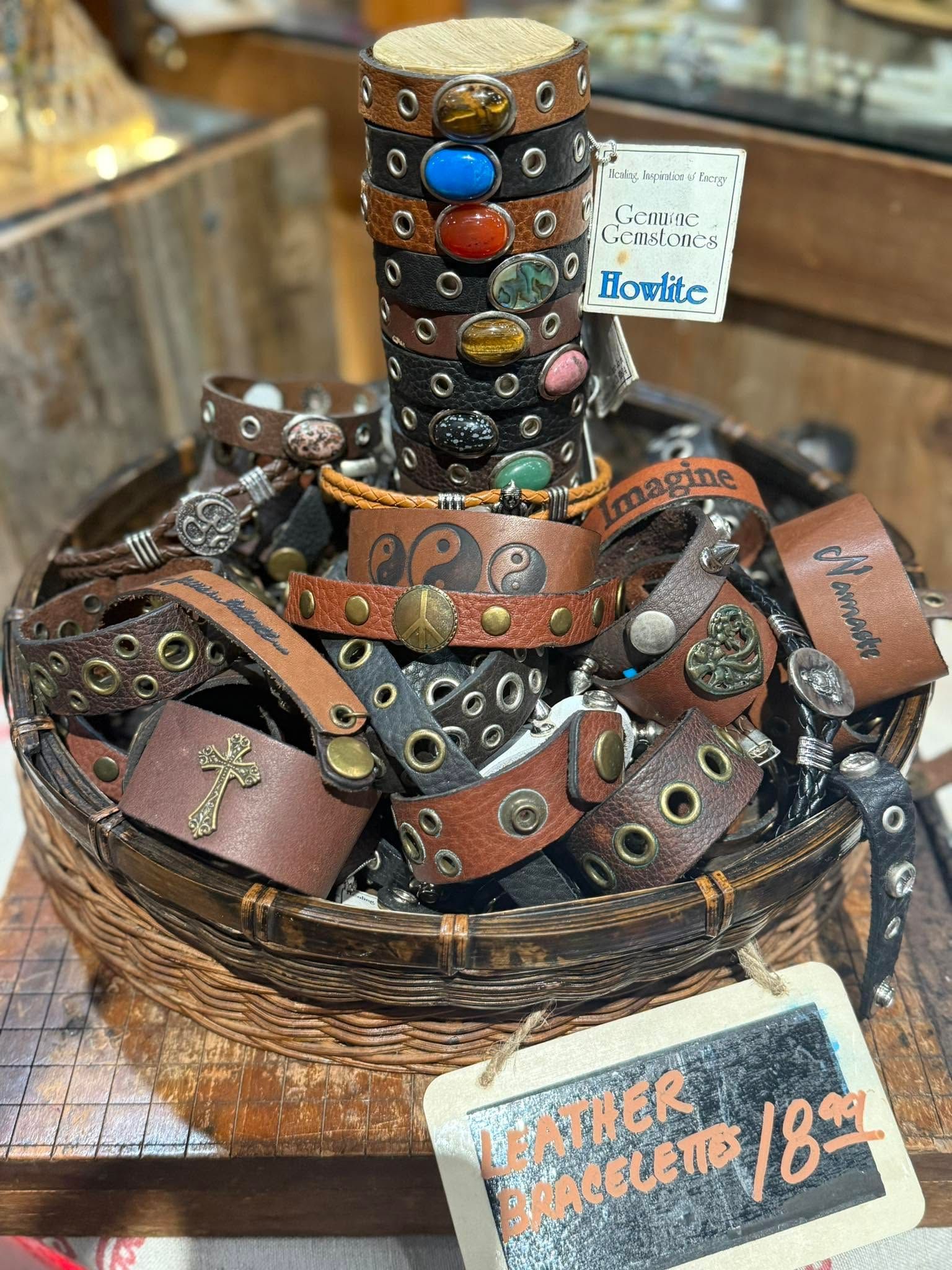 Stacked leather bracelets with metal studs and colorful beads in a woven basket at a market stall