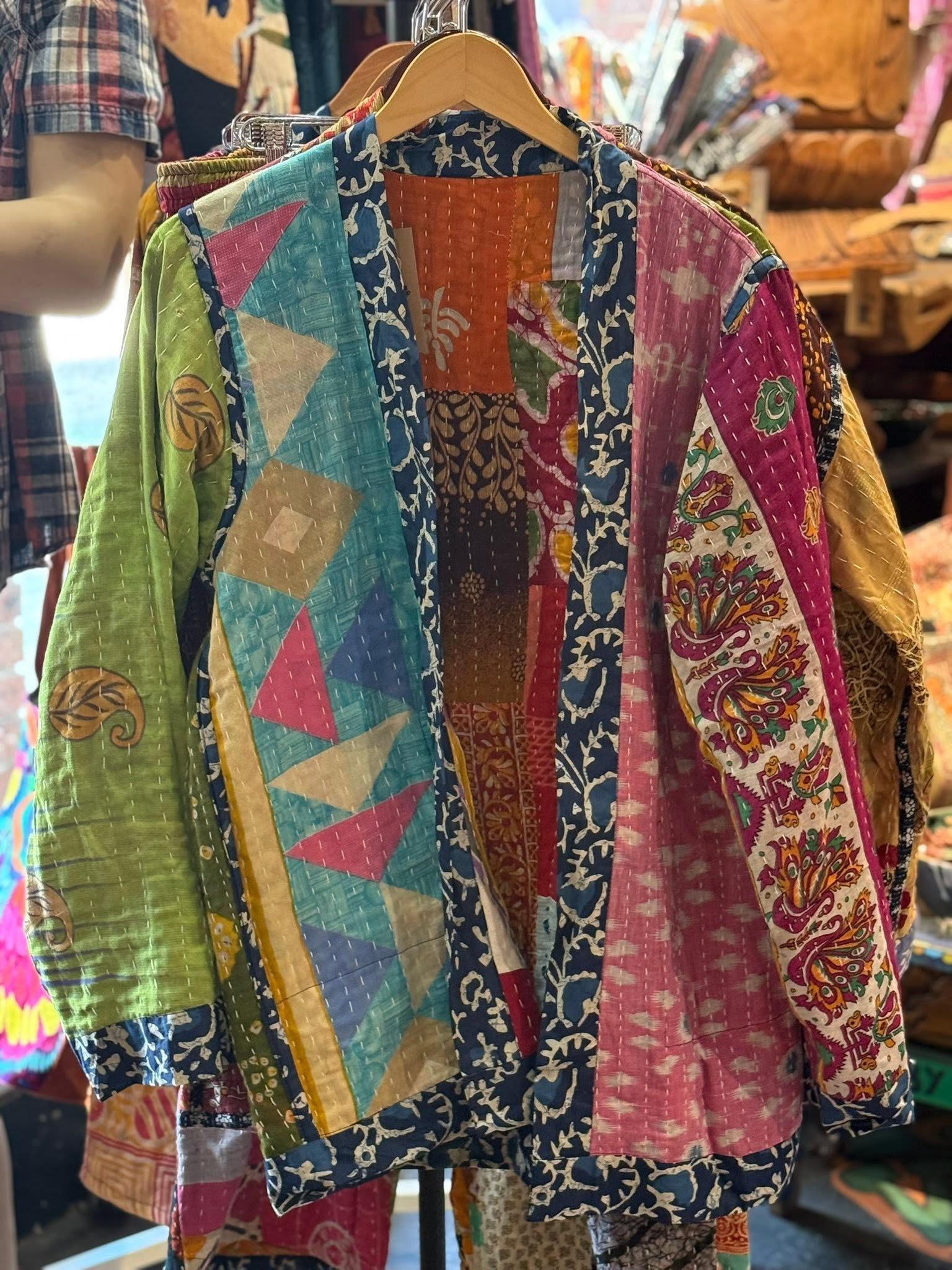 Colorful patchwork jacket on a hanger at a clothing market booth