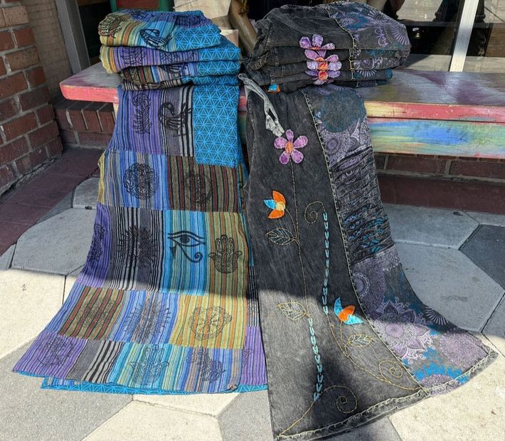 Two colorful patchwork quilts draped over a bench, one blue and one black with butterfly designs.