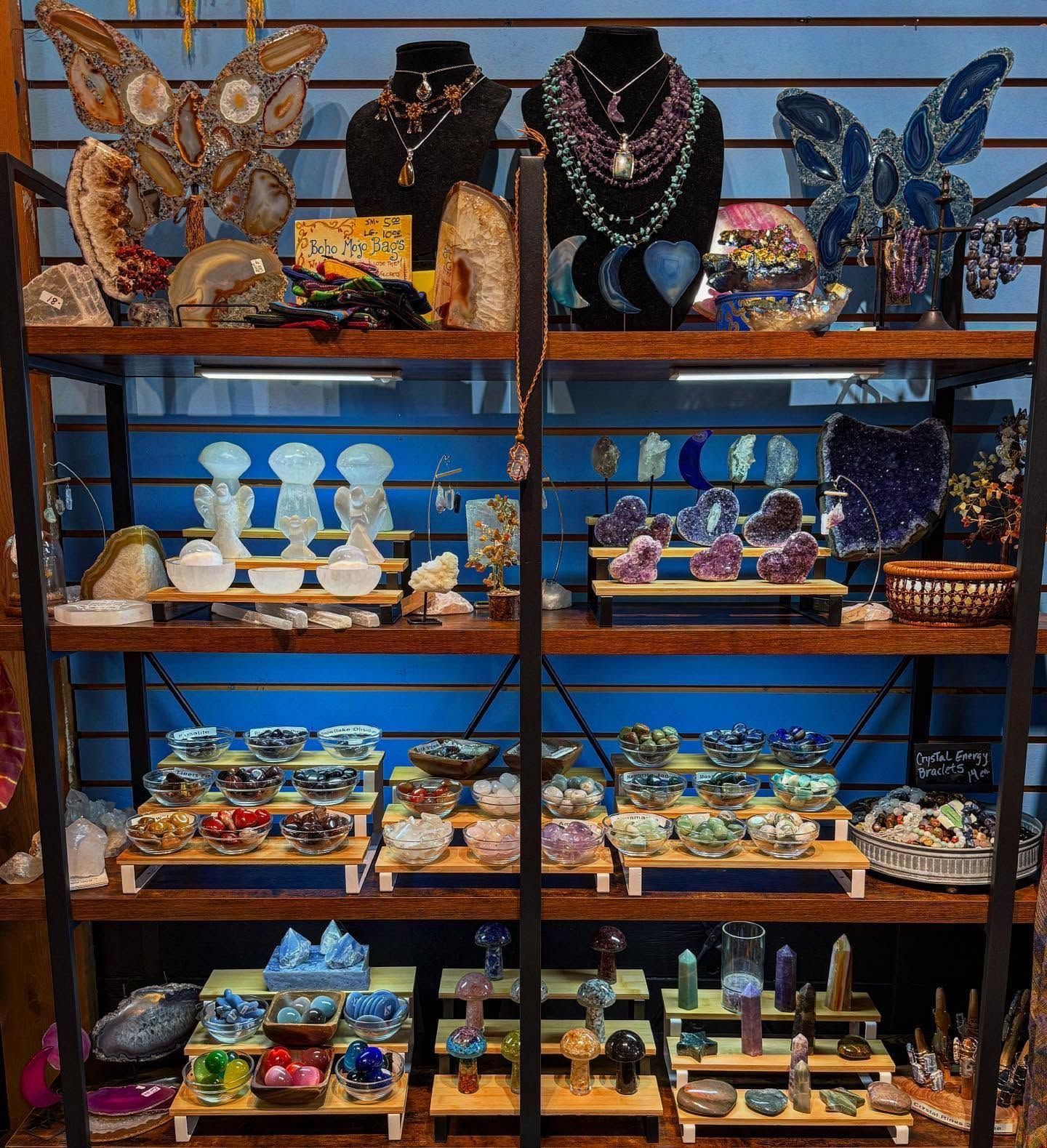 Shelves of colorful crystal and gemstone jewelry, figurines, and decorative items in a shop display