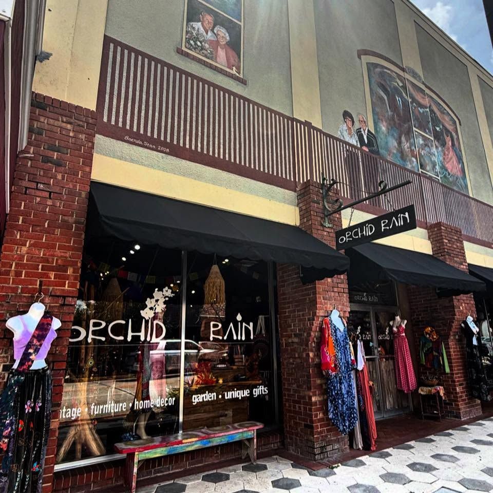 Storefront of Orchid Rain with colorful clothing racks under a brick-and-cream building facade