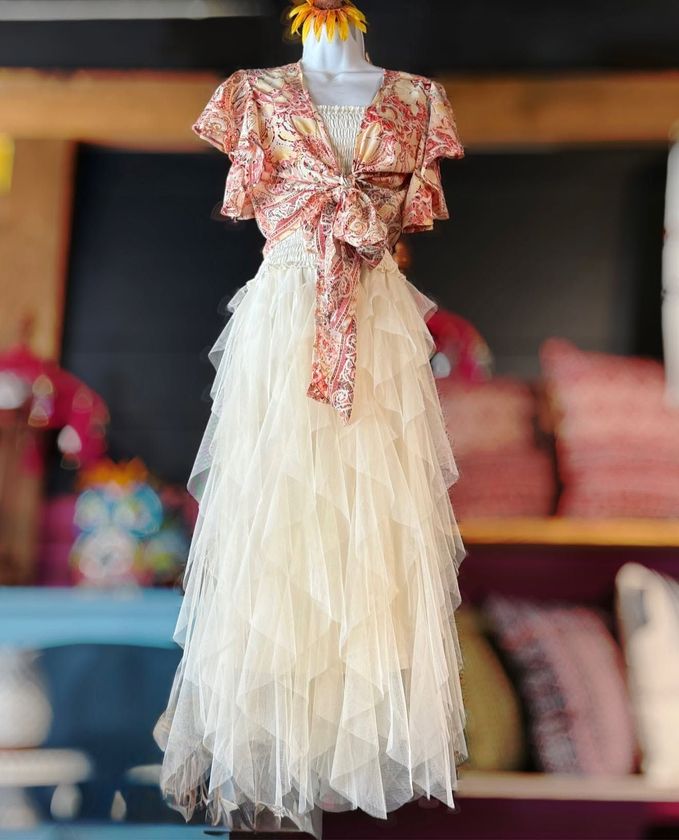 White tulle dress with pink floral bow on a mannequin, displayed in a shop