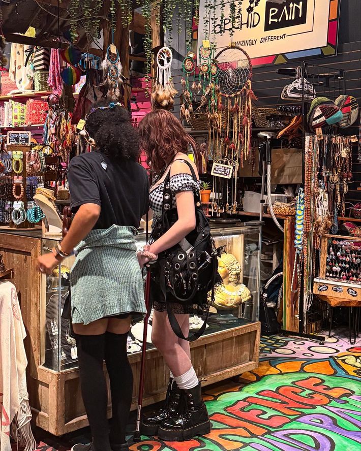 Two people browsing colorful items in a crowded gift shop.