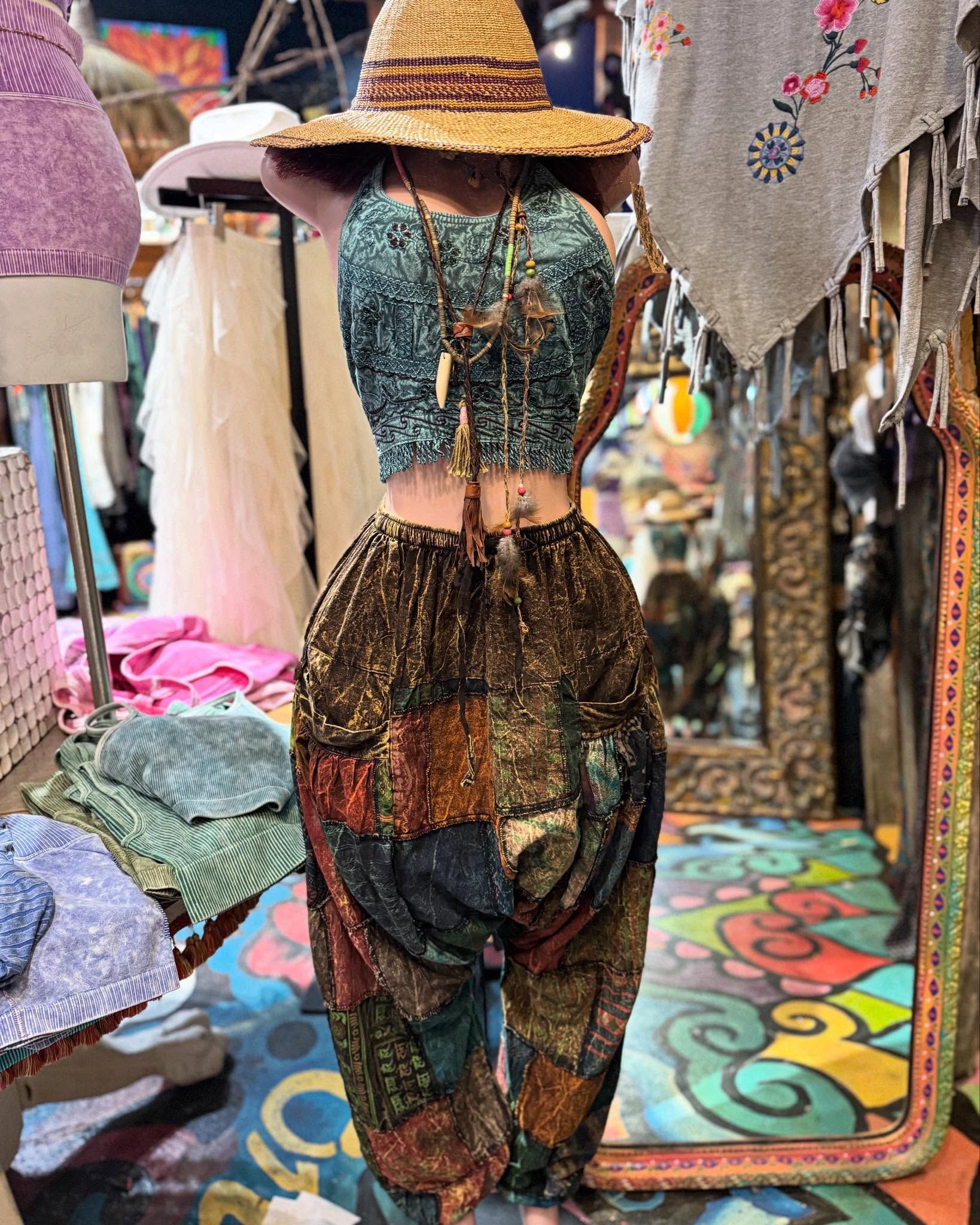 Patterned dress and straw hat on a mannequin in a colorful clothing shop display