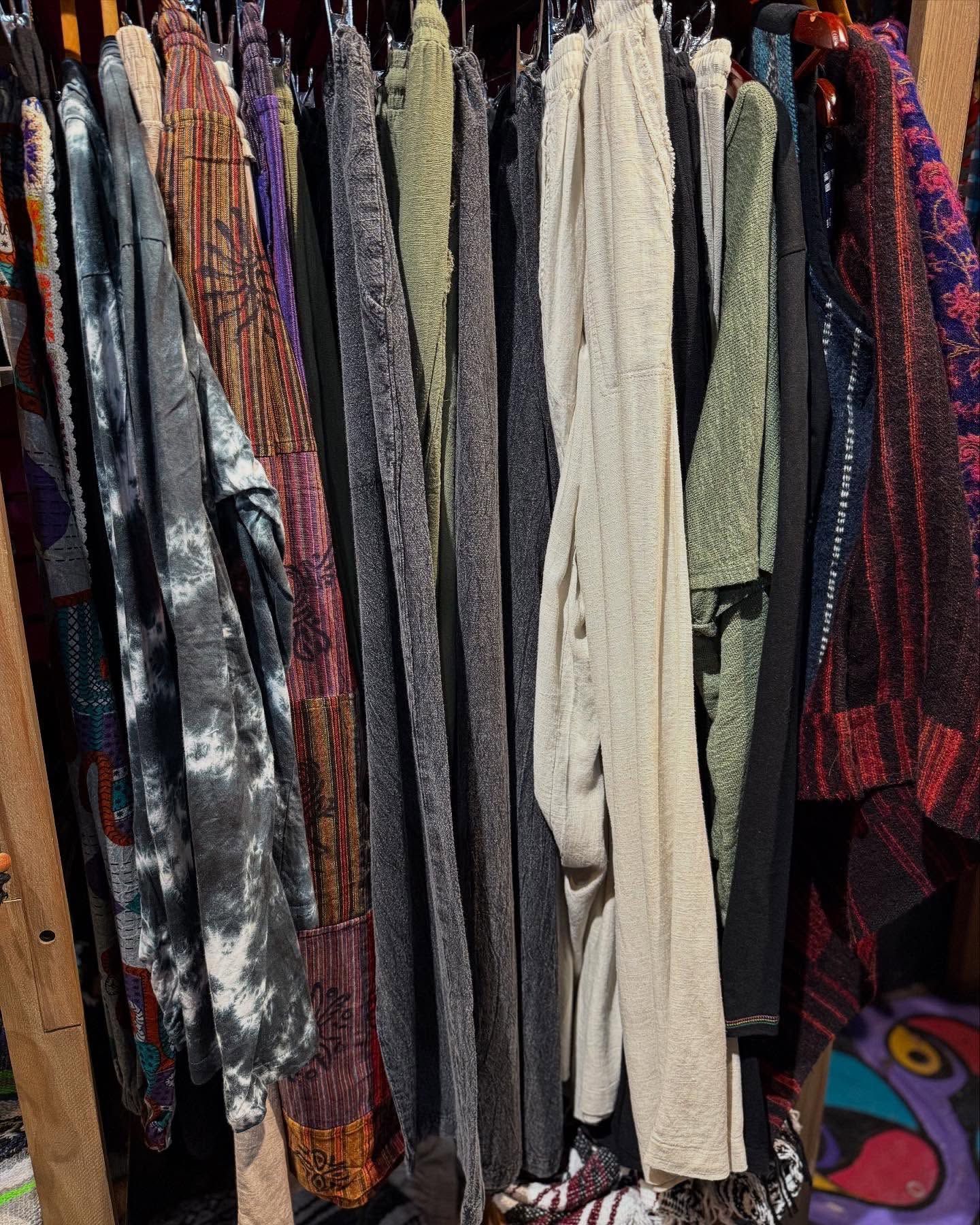 Assorted patterned clothes hanging tightly on a clothing rack in a closet