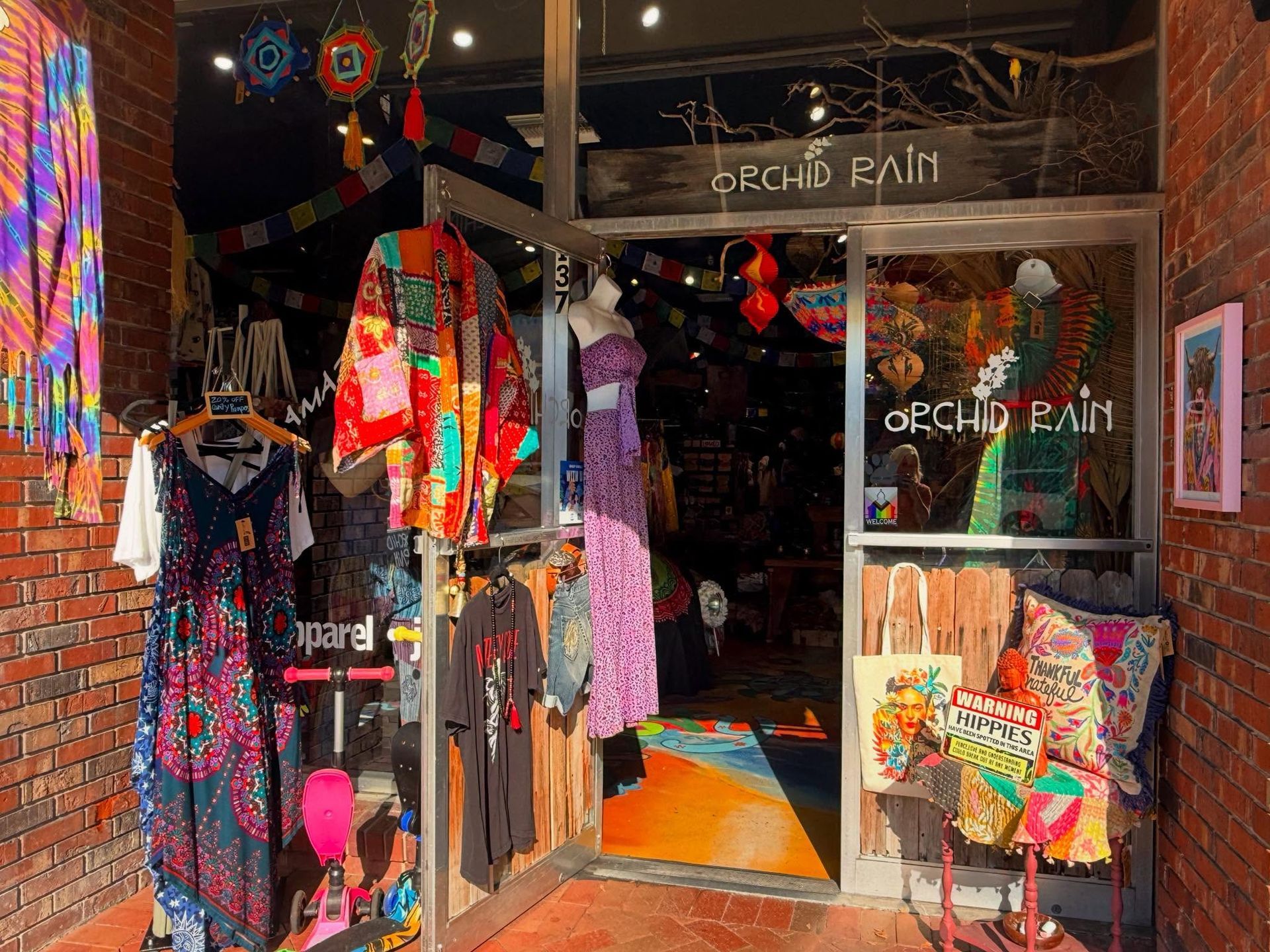 Colorful boutique storefront with hanging clothes and patterned fabrics by the entrance