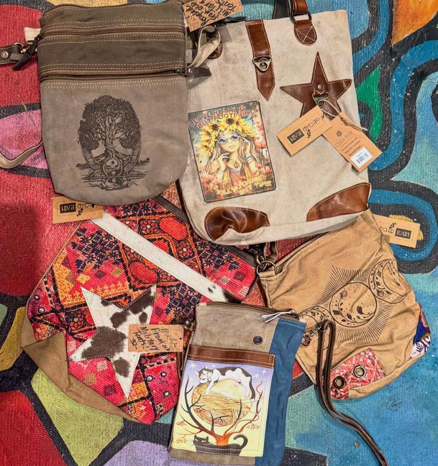 Assorted handmade bags and pouches with colorful patterns laid out on a patterned surface