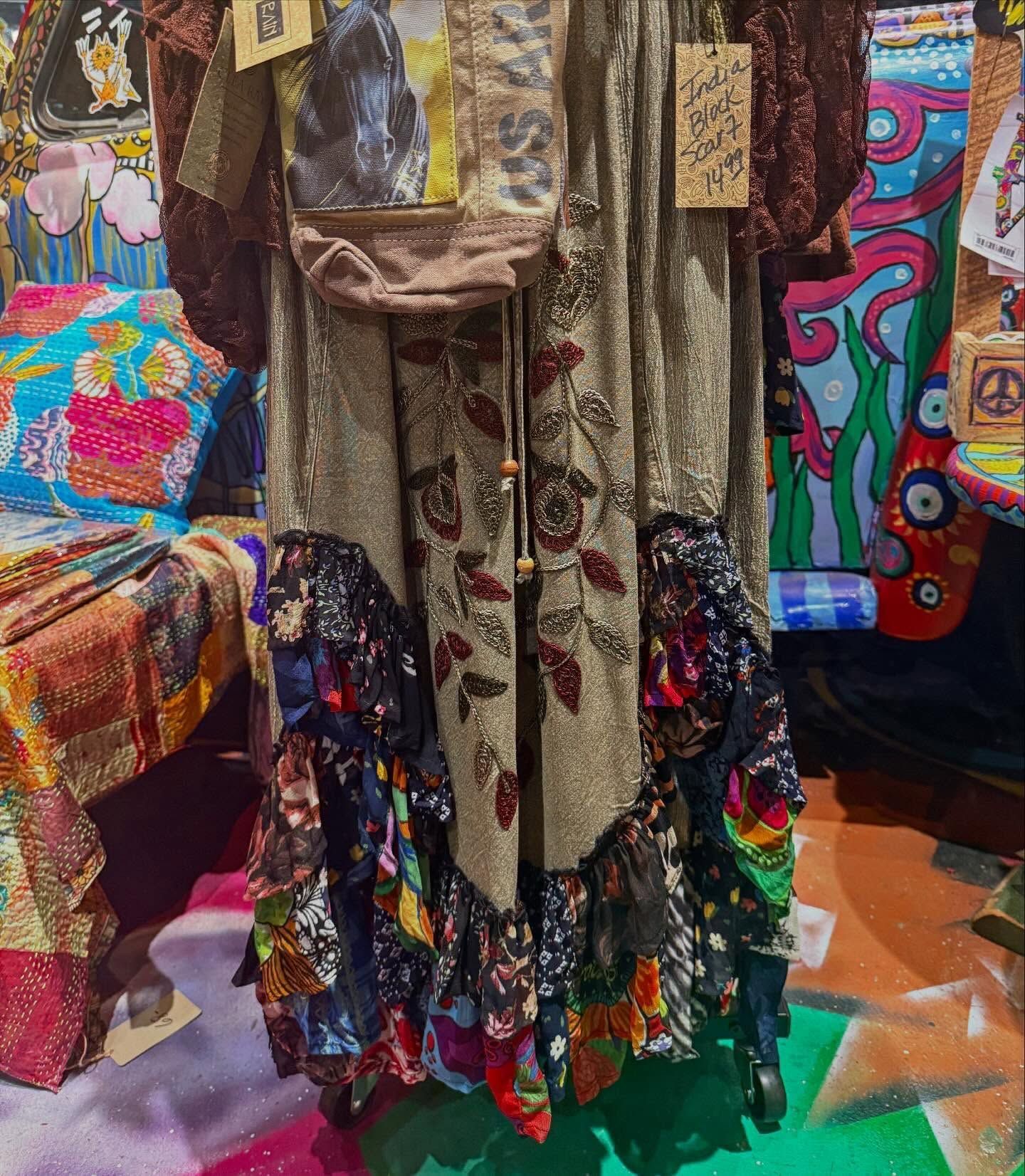 Colorful patterned dresses and bags displayed in a boutique, with bright textiles and a decorated floor.
