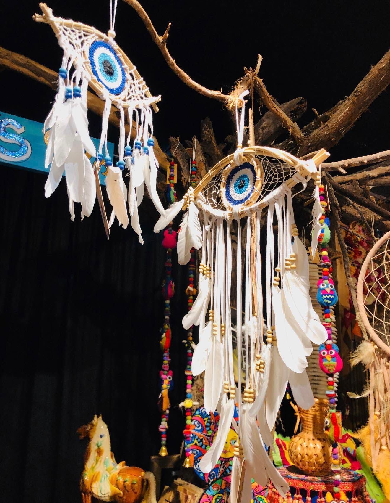 Decorative dreamcatchers with white feathers and colorful beads hanging from branches