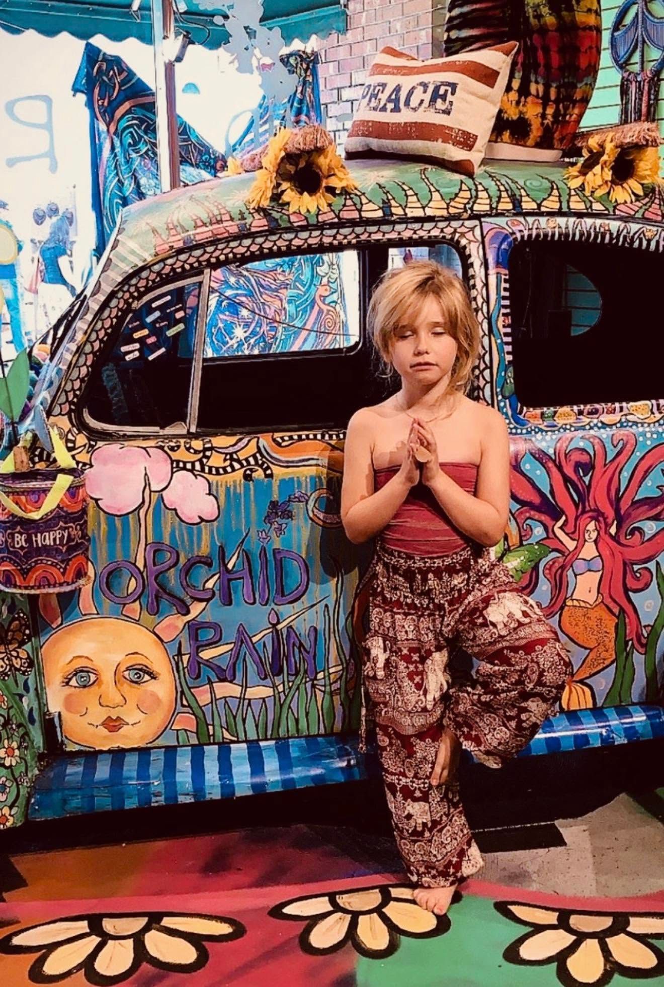 Person standing in front of a colorful, graffiti-covered van decorated with flowers and peace signs