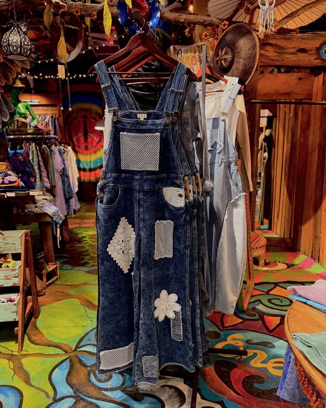 Bohemian shop display with blue patchwork denim outfit and colorful woven textiles behind it