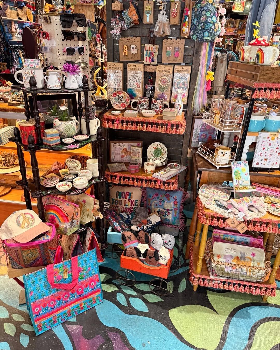 Colorful display of handmade crafts, mugs, and trinkets on shelves and tables in a shop