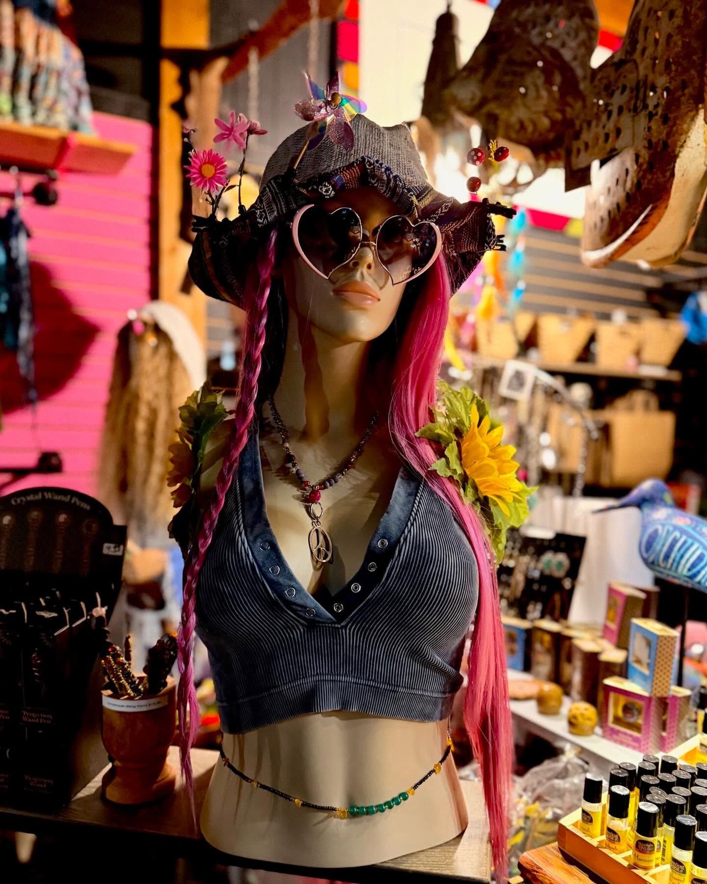 Mannequin in a boho hat, sunglasses, and patterned top in a colorful market stall