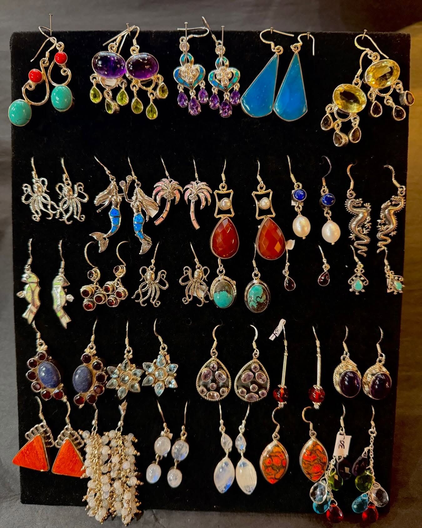 Assorted colorful dangling earrings displayed on a black background.