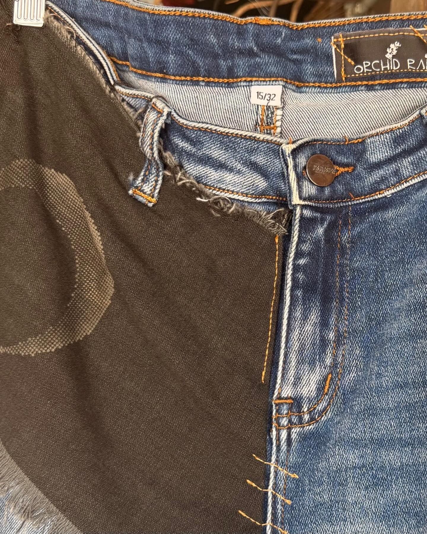 Close-up of two-tone denim pants with a brown corduroy panel and visible button fly.