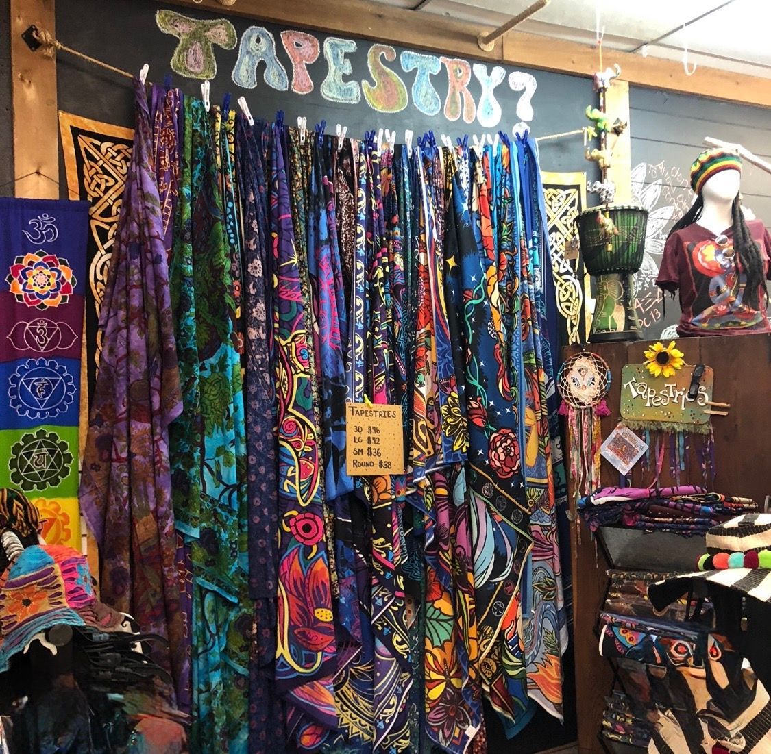 Colorful tie-dye shop display with hanging shirts, tapestry curtain, and bohemian decor