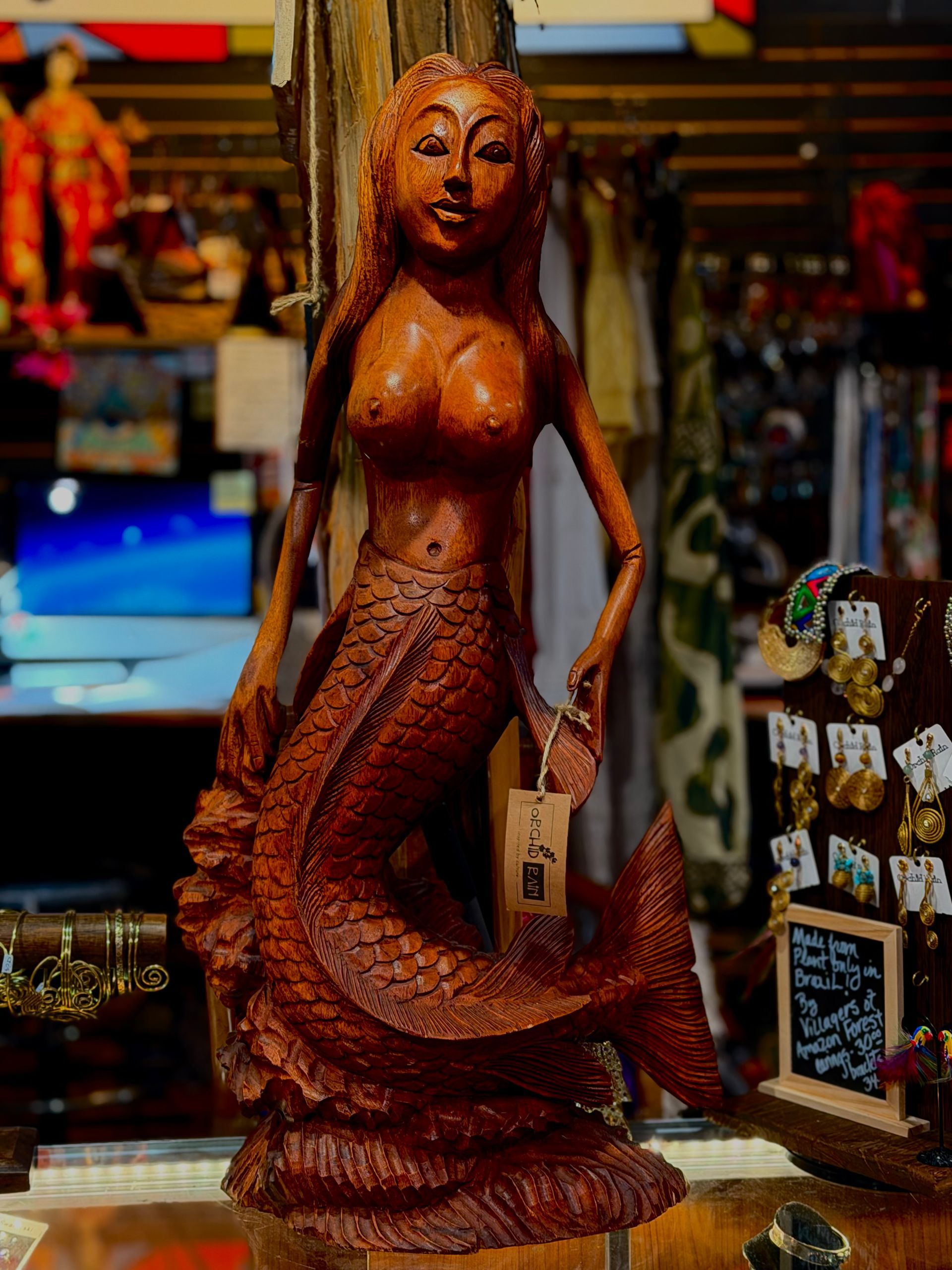 Wooden mermaid statue with a carved woman’s torso and fish tail displayed in a shop