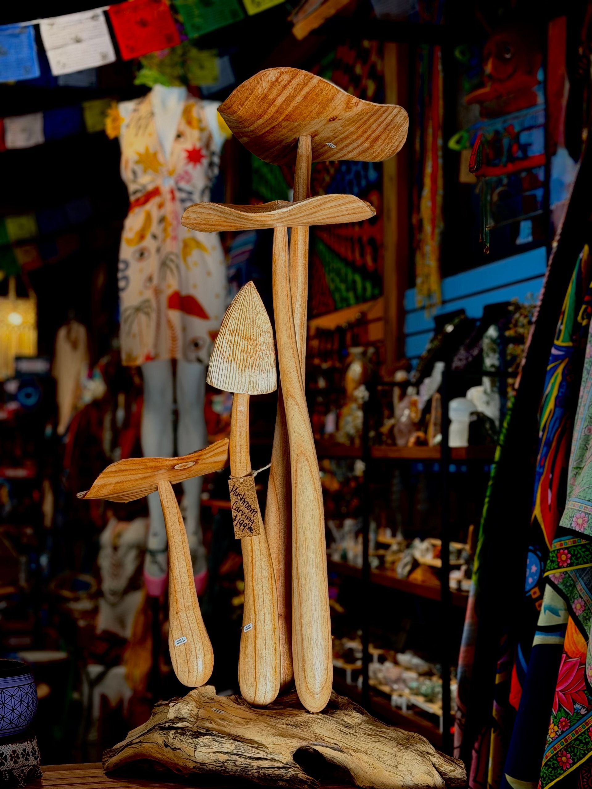 Carved wooden totem-like sculpture with braided fibers, displayed in a colorful market stall