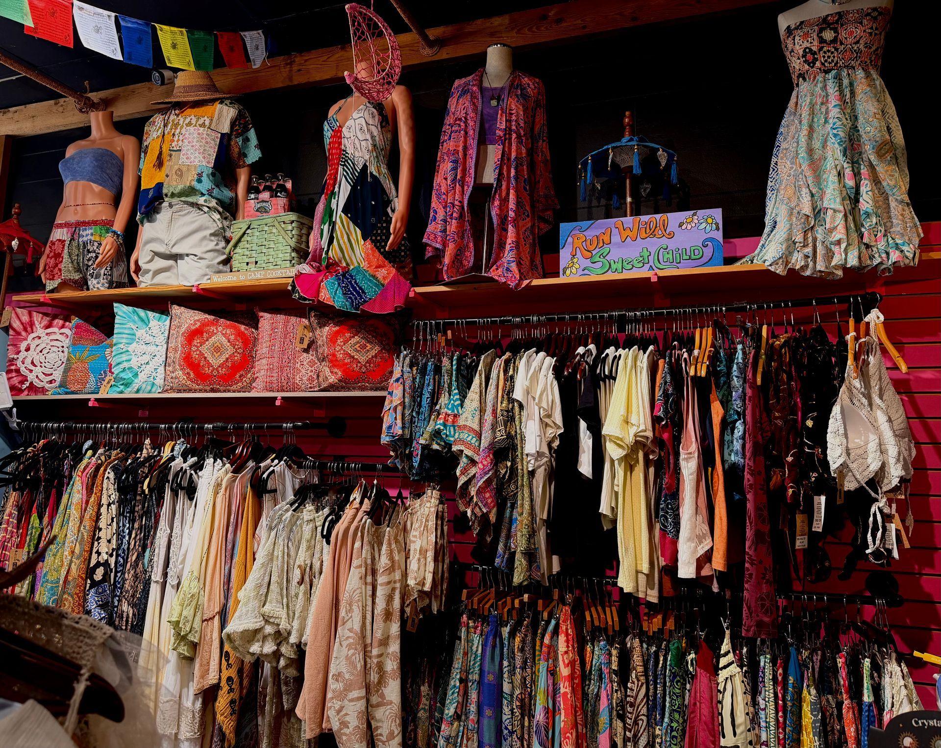 Colorful clothing and accessories displayed in a crowded market stall with hanging garments and skirts