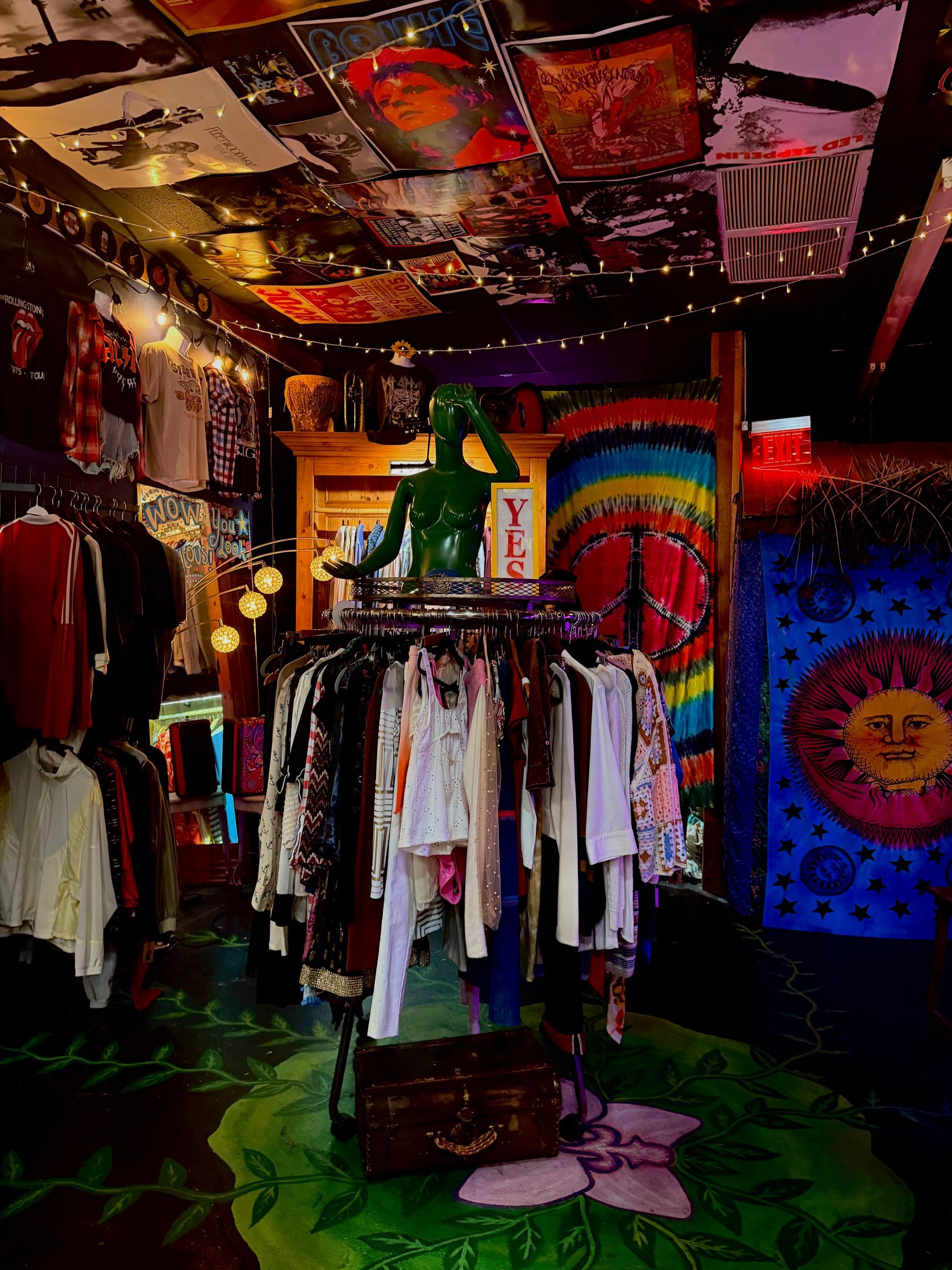 Colorful clothing shop interior with hanging clothes, vibrant murals, and a mannequin near the center