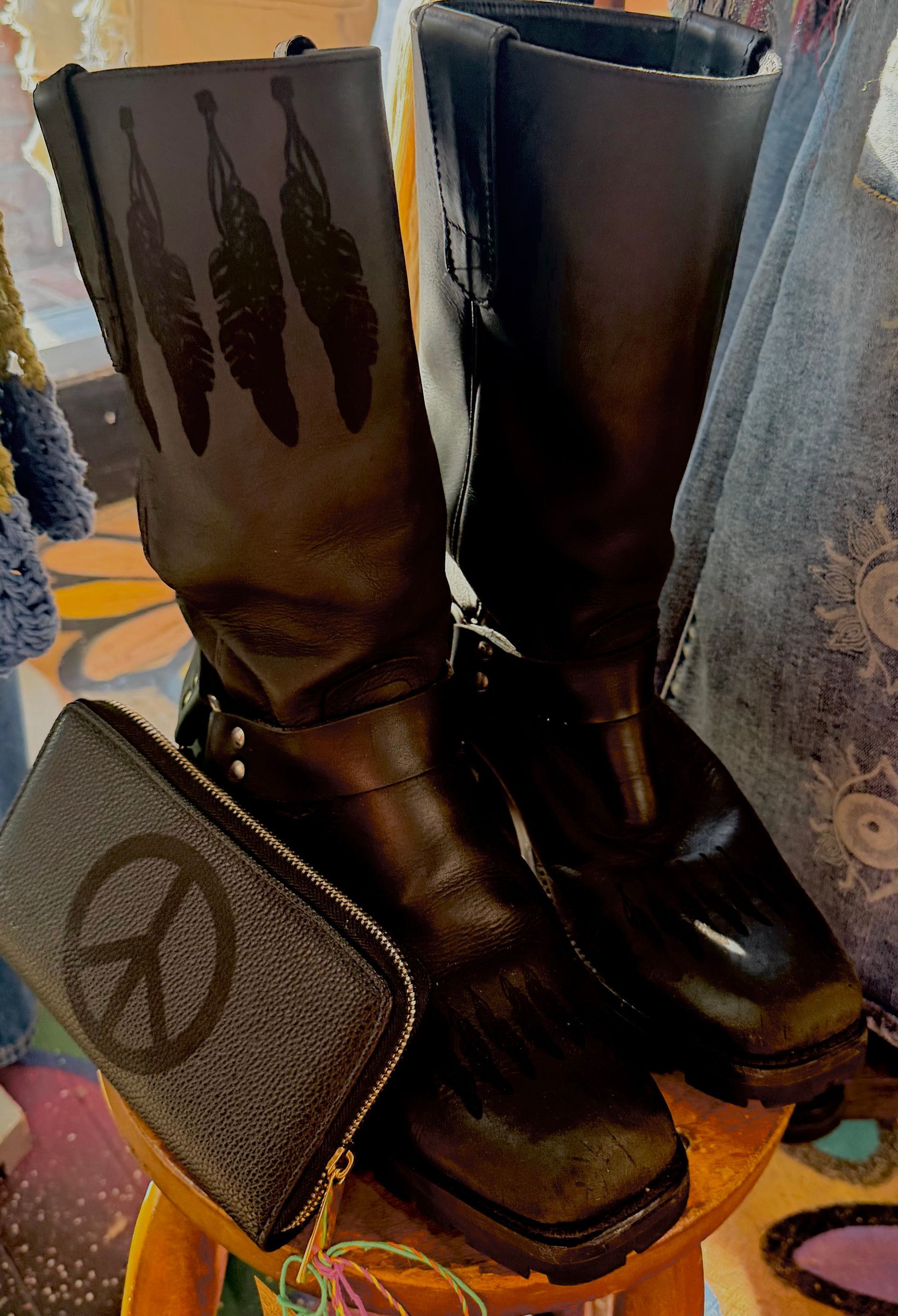 Black knee-high boots with a peace-sign bag displayed on a store floor.