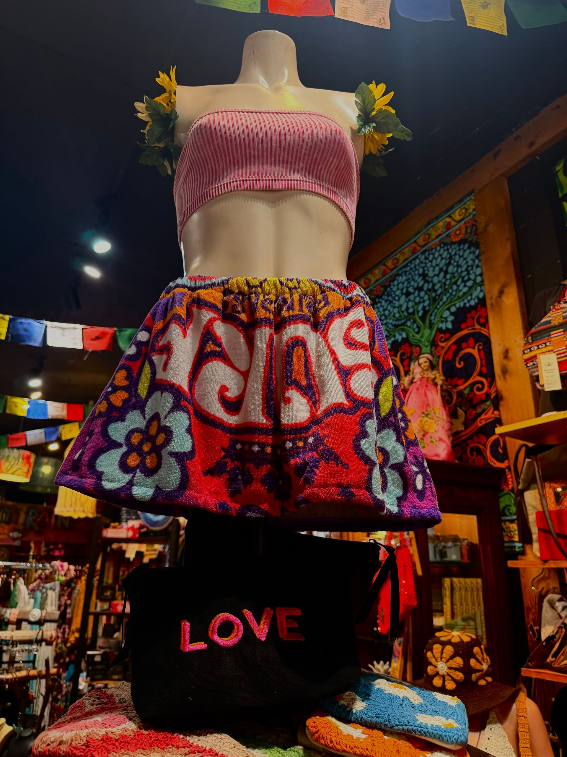 Colorful mannequin in a folk-art dress with flowers and “LOVE” text in a vibrant shop display