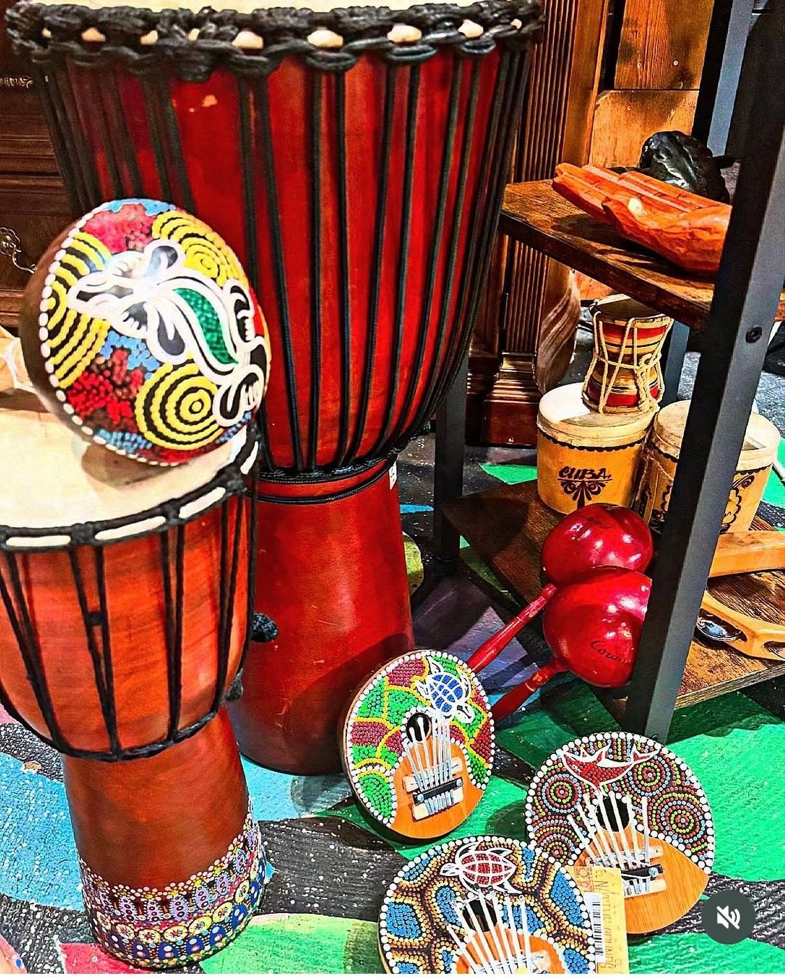 Colorful hand drums and rattles displayed on a shop shelf with beaded decorations