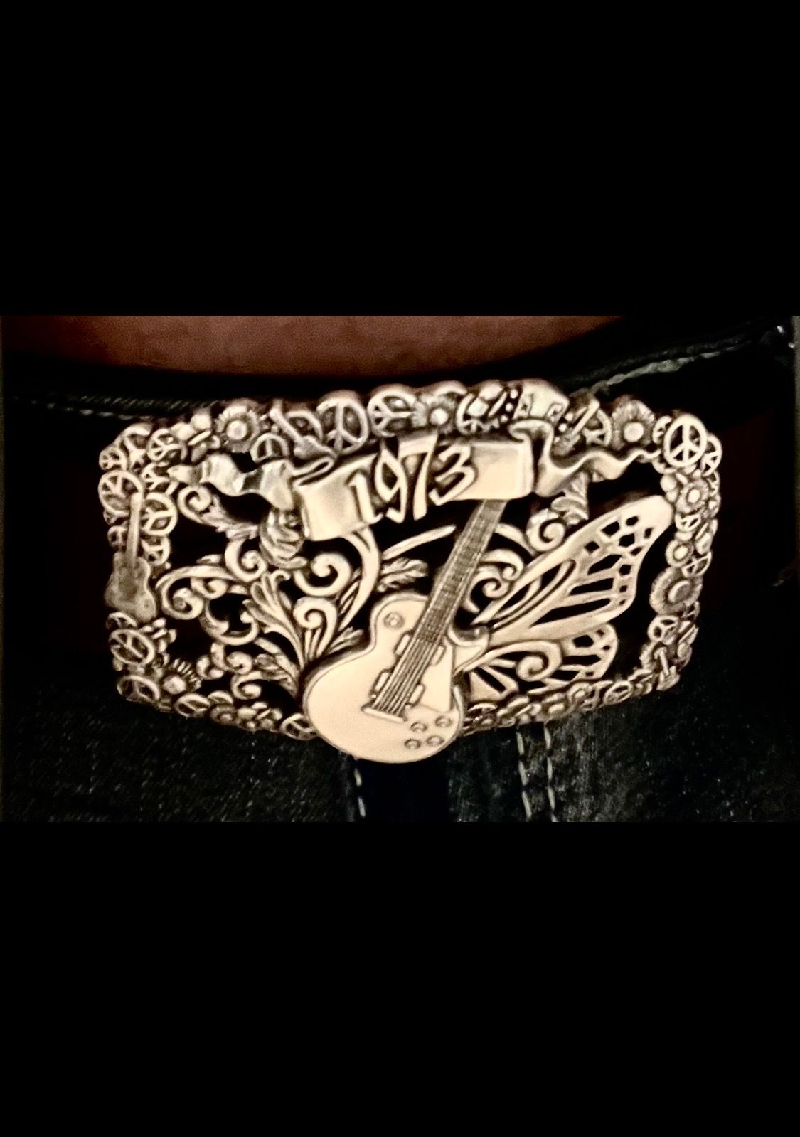 Close-up of an ornate silver-and-black belt buckle with “1973” engraved on it