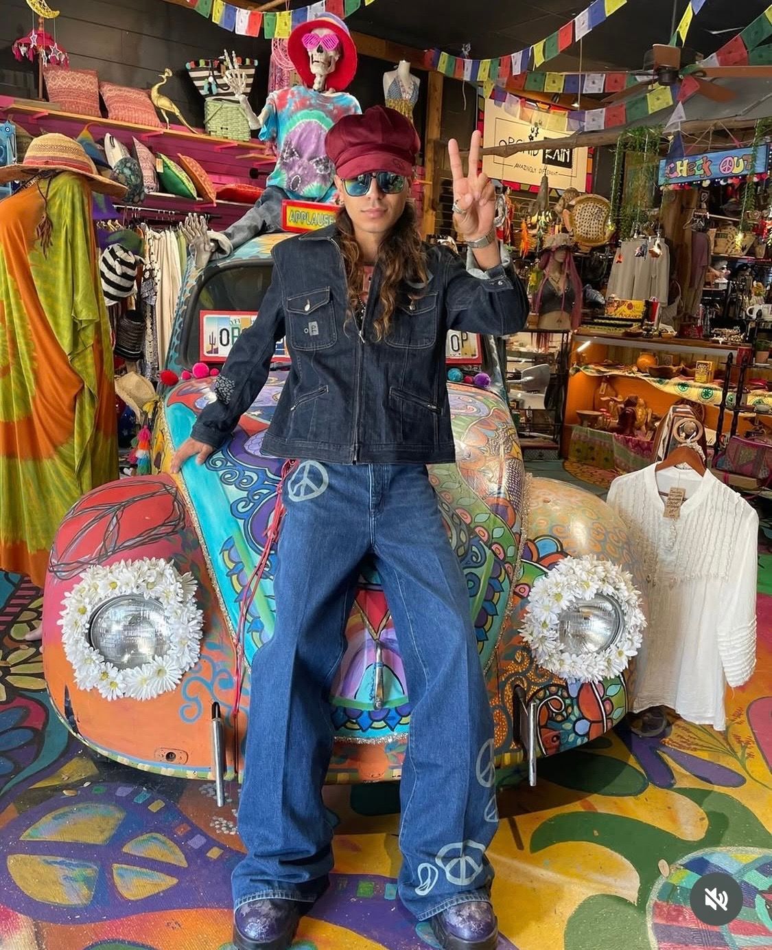 Person in denim and sunglasses stands in a colorful, eclectic shop filled with vibrant textiles and decor.