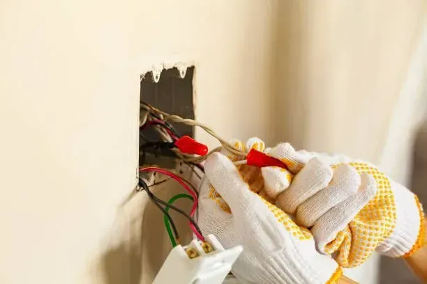 Person with gloved hands wiring an electrical outlet in a wall. Person with gloved hands wiring an electrical outlet in a wall.
