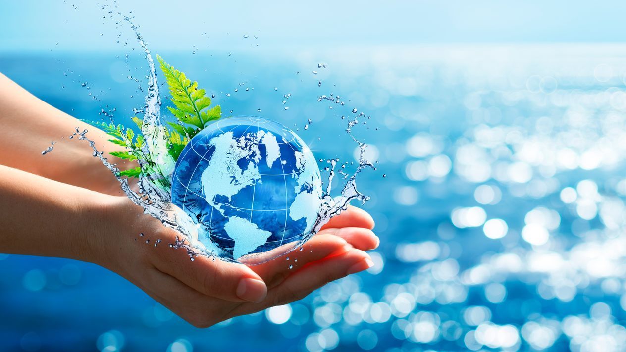 A person is holding a globe in their hands with water splashing around it.