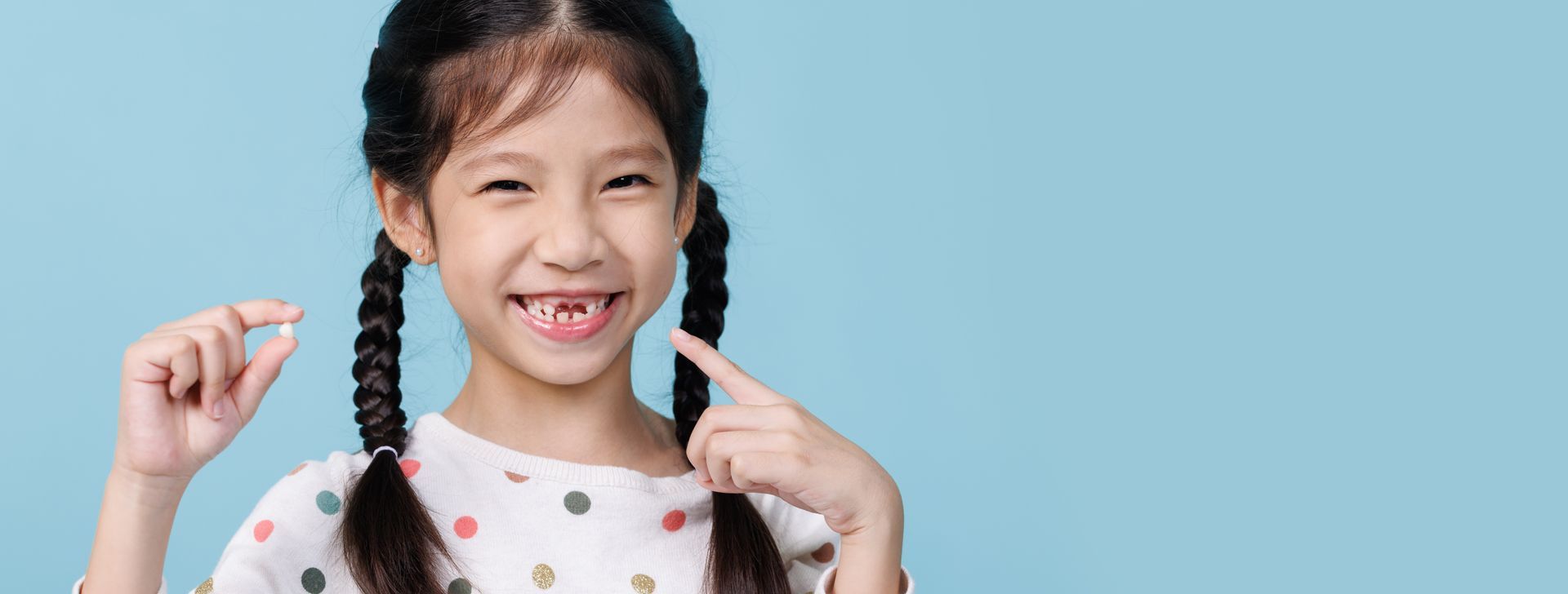 A young girl holding one of her tooth