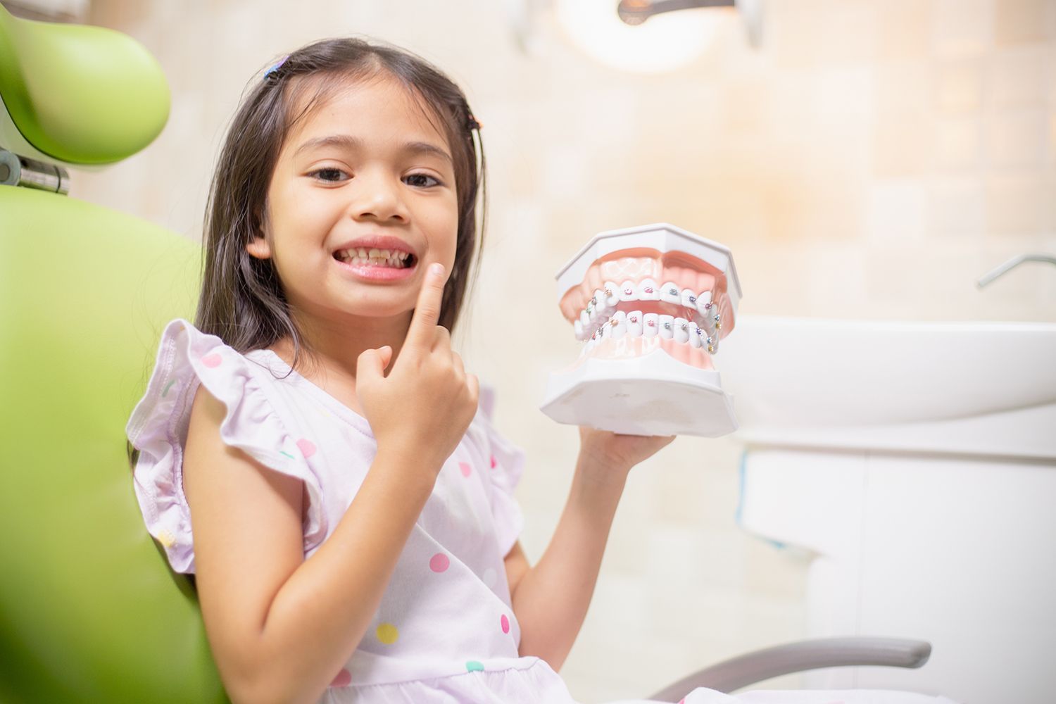 A young Girl holding a teeth model