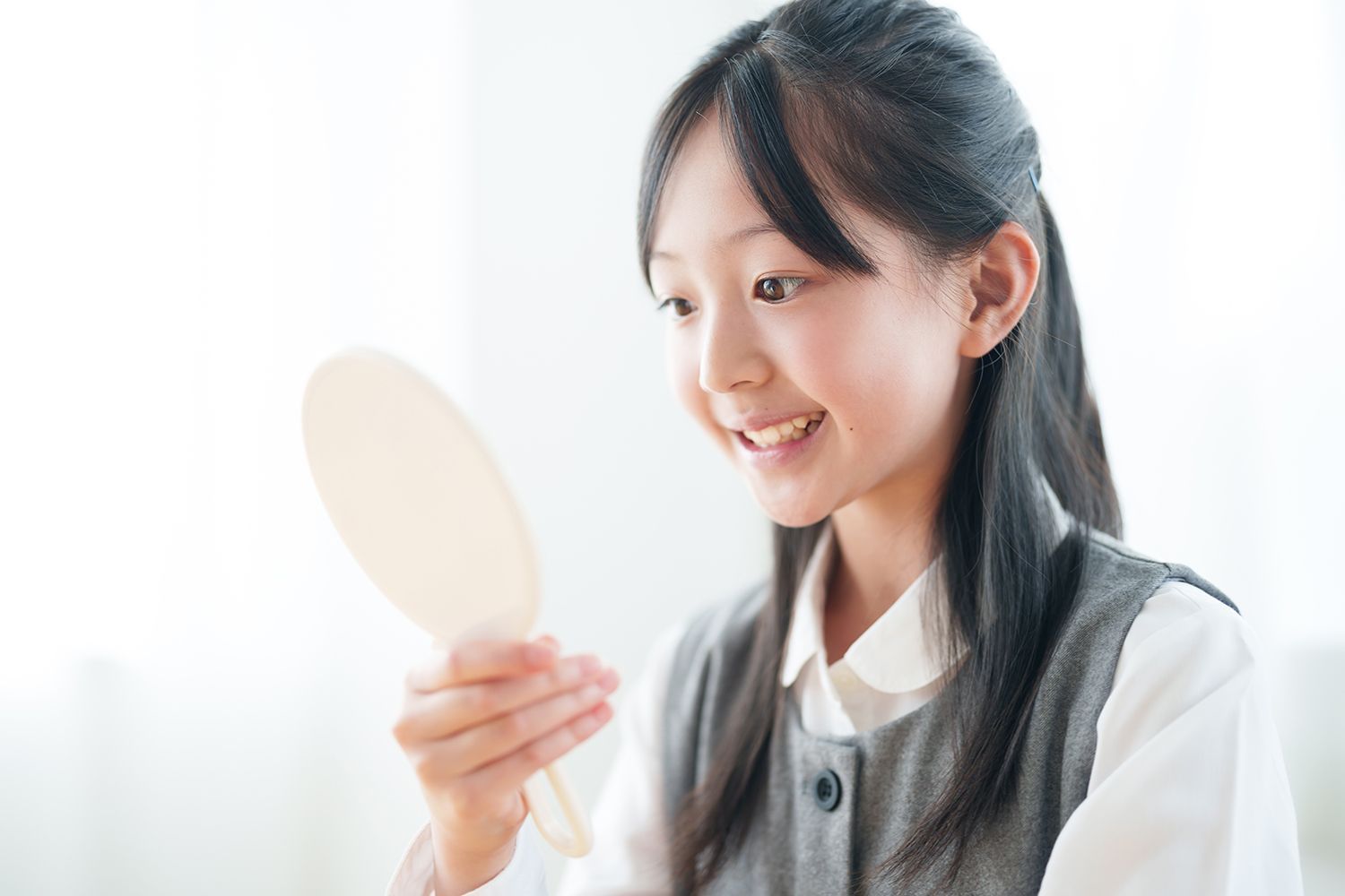 A girl looking at her teeth on a mirror