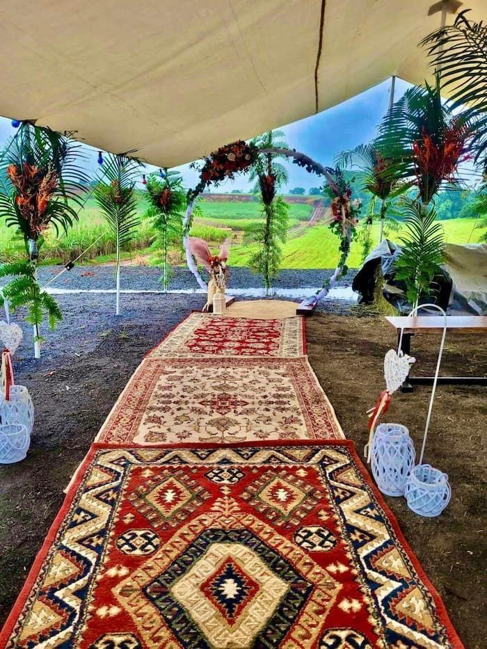 Outdoor Wedding Aisle With Patterned Rugs, Floral Decor, and Natural Background — Creative Events Innisfail in Babinda, QLD