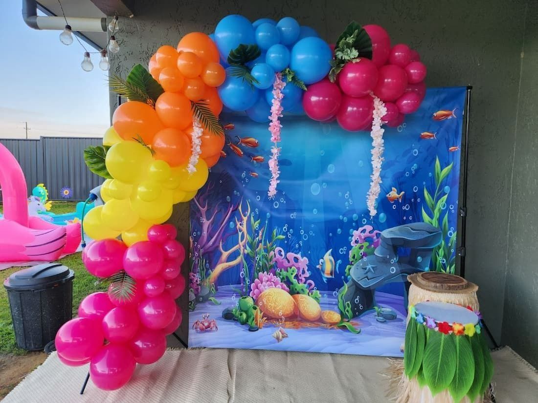 Colorful Balloon Arch With an Ocean Backdrop, Near a Pink Inflatable Flamingo — Creative Events Innisfail in Innisfail, QLD