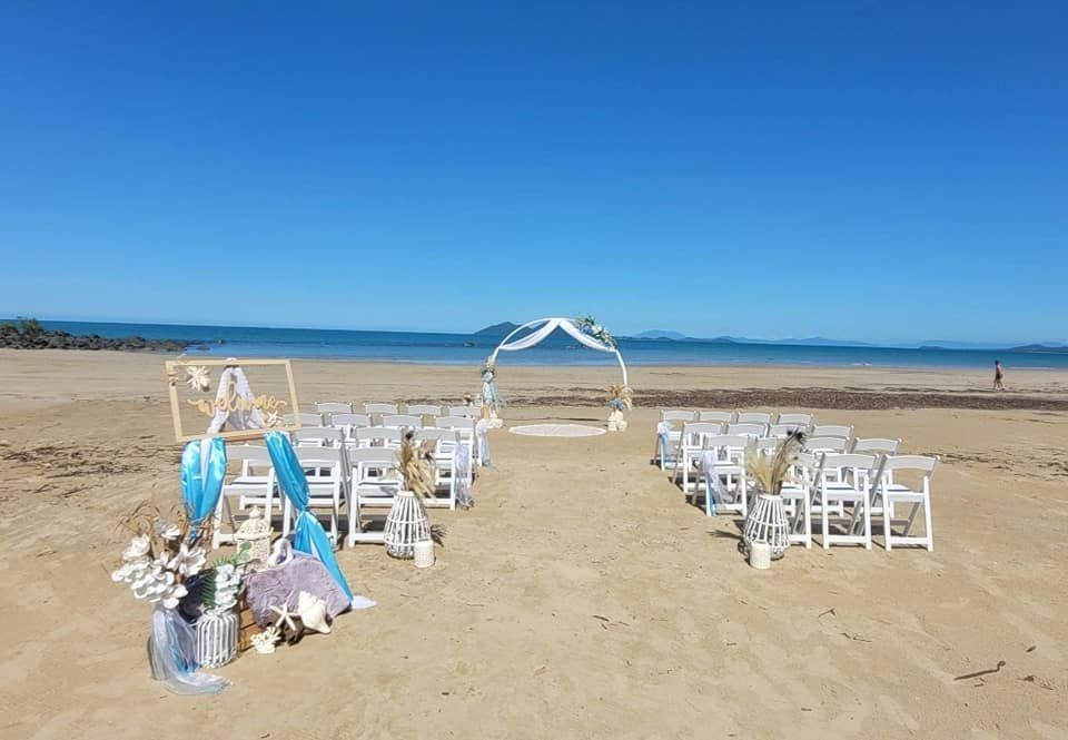 Wedding Setup on a Beach With White Chairs, Arch, and Decorations — Creative Events Innisfail in Babinda, QLD