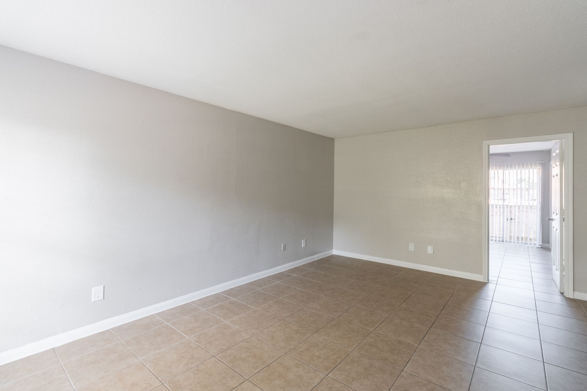 An empty living room with a tiled floor and white walls.