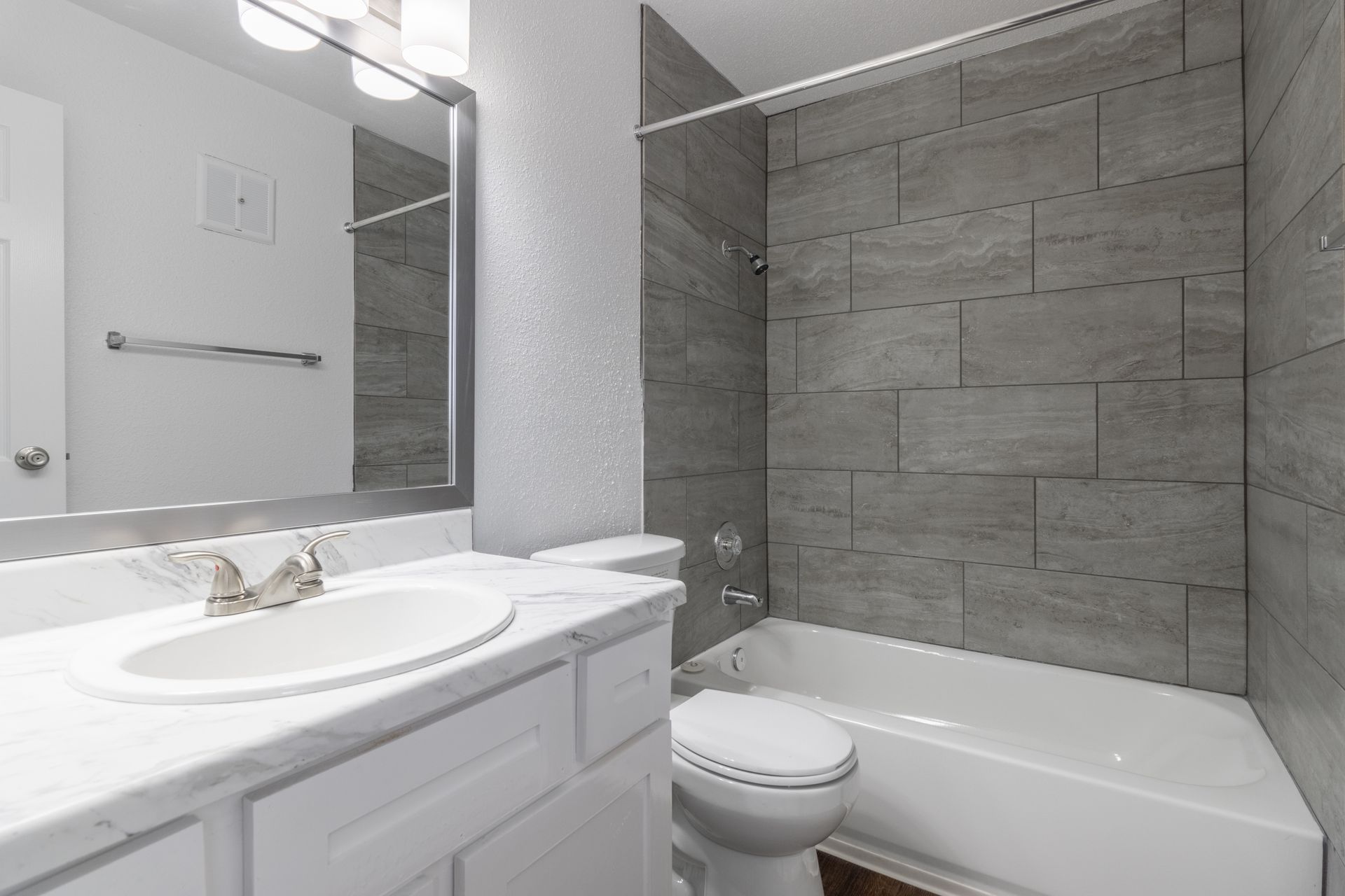 A bathroom with a sink , toilet , bathtub and mirror.