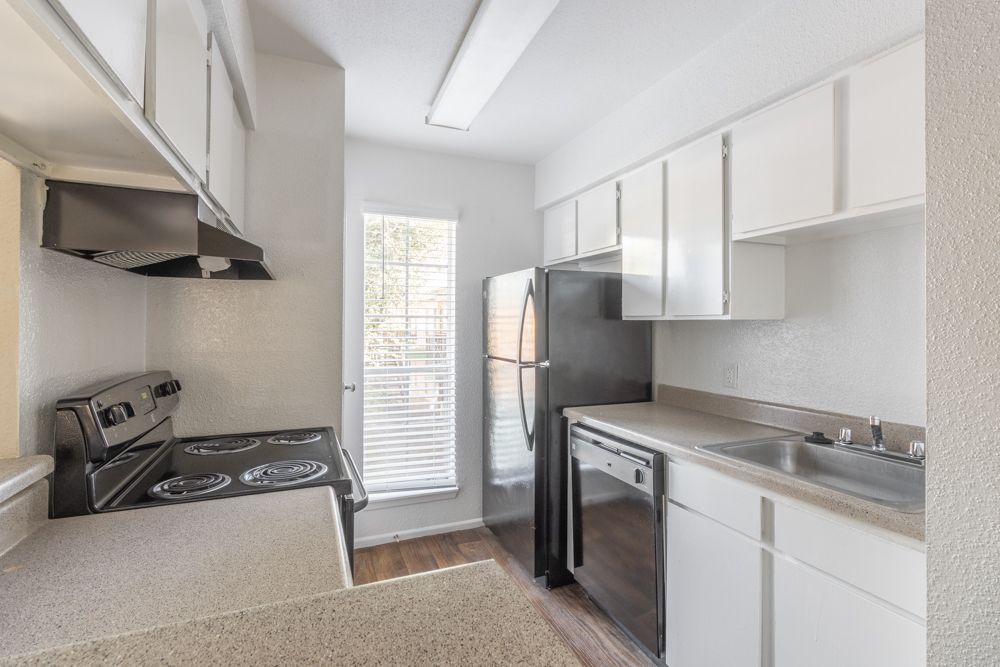 A kitchen with a stove , refrigerator , dishwasher and sink.