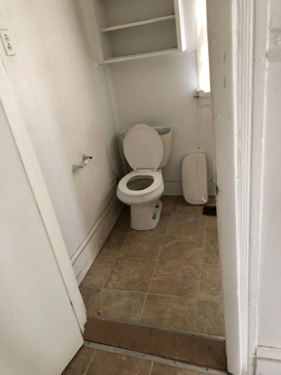 A toilet is sitting in a bathroom next to a door.