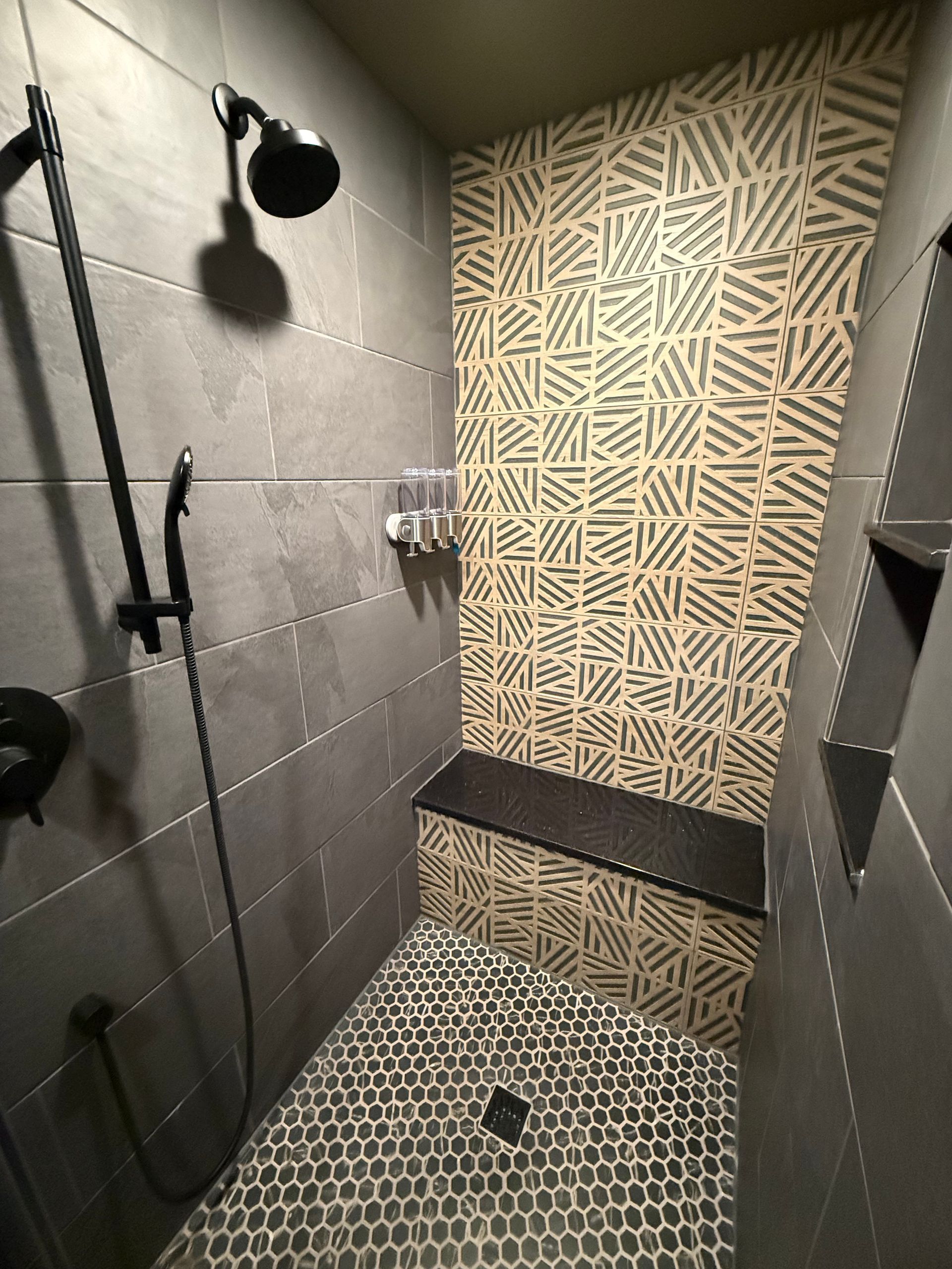 A shower with a bench and a shower head.