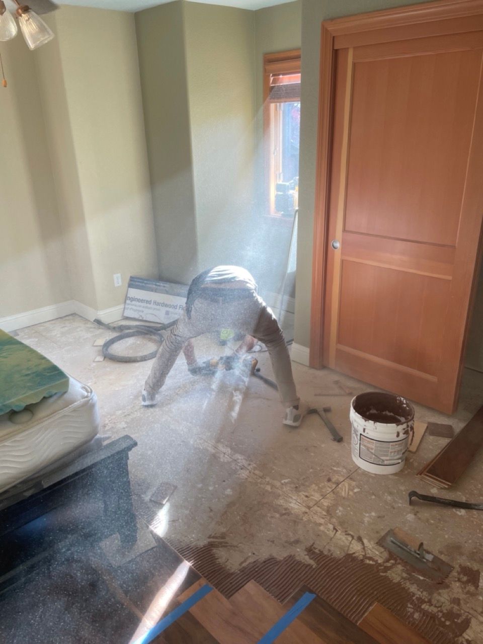 A man is laying wood flooring in a bedroom.