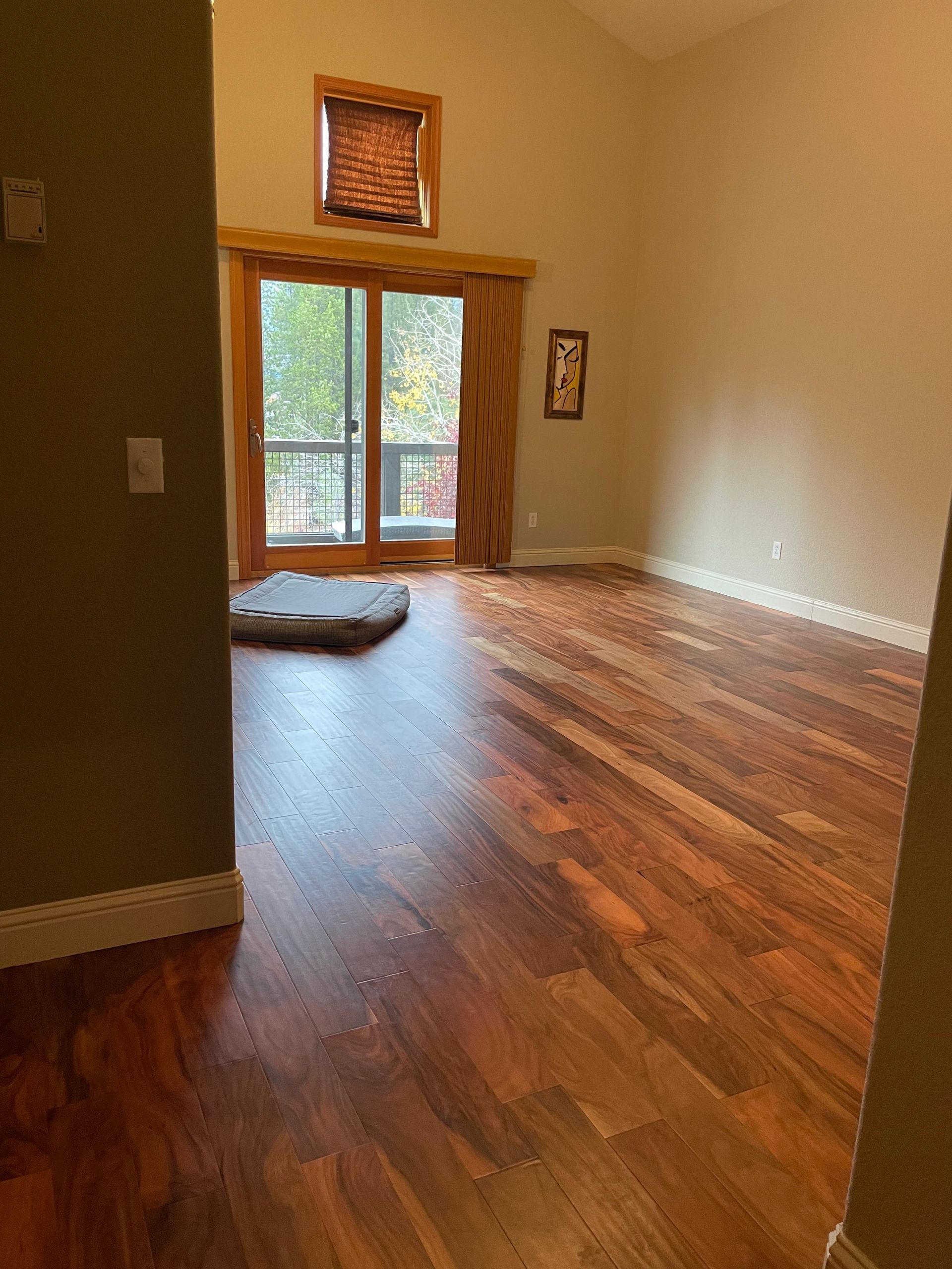 An empty living room with hardwood floors and a sliding glass door.
