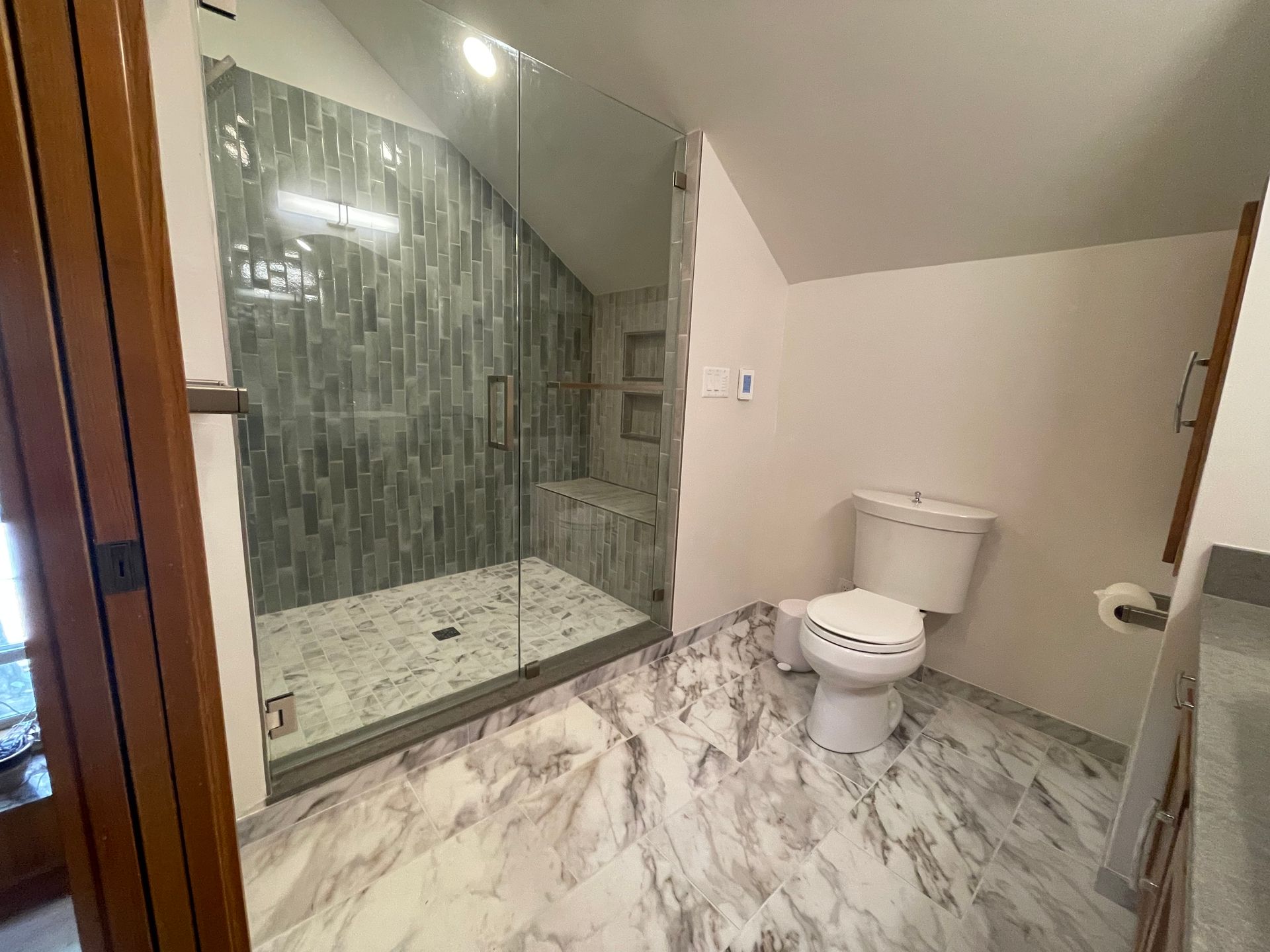 A bathroom with a toilet , shower and marble floor.