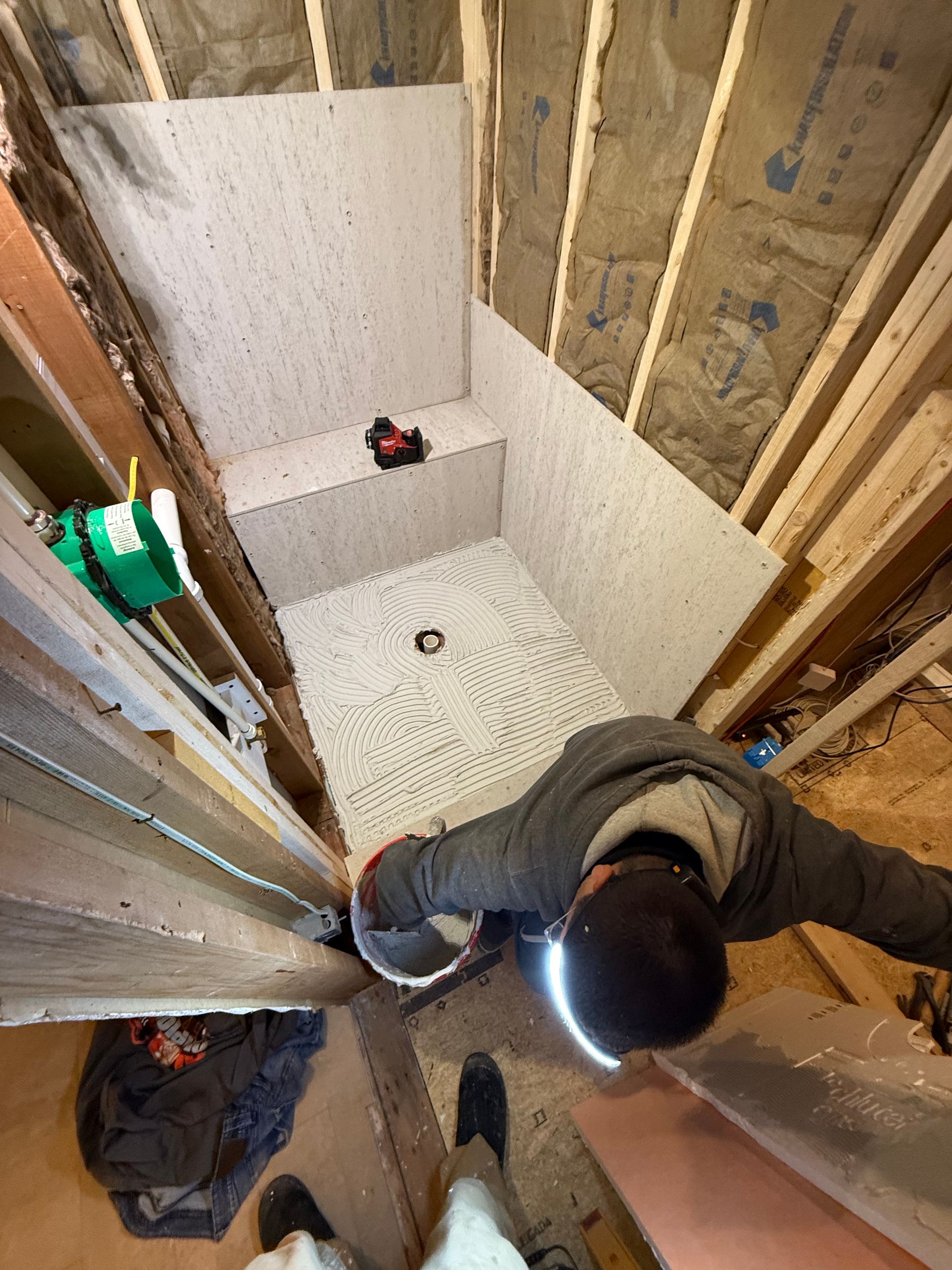 A man is standing in a bathroom under construction.