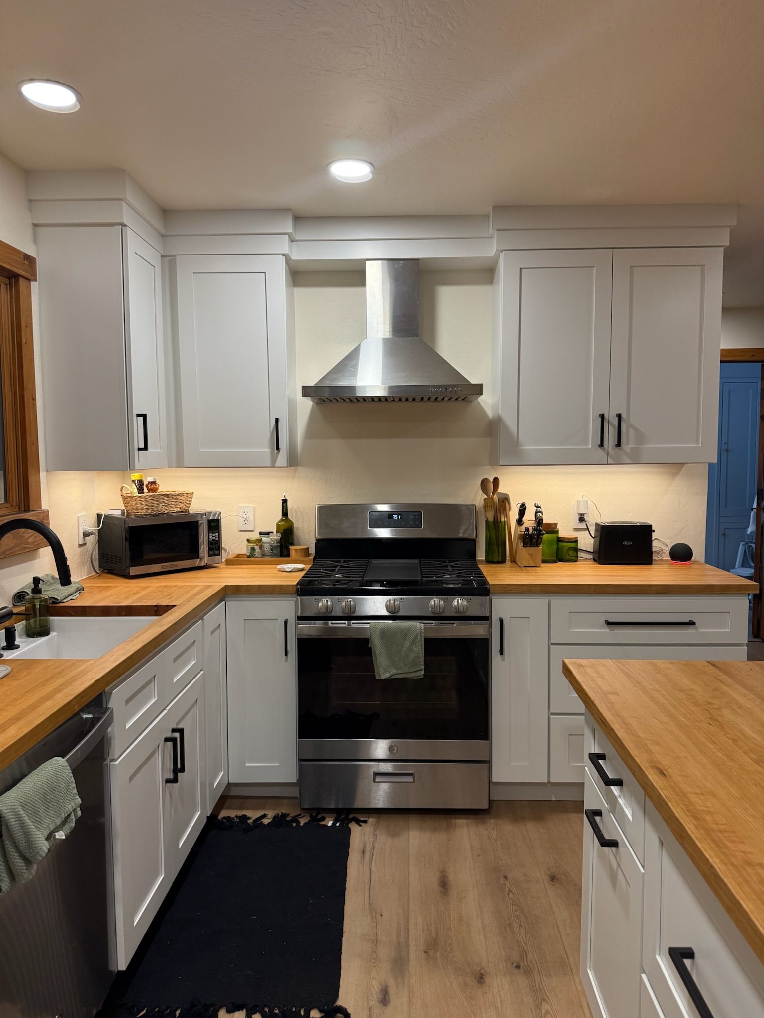 A kitchen with a large island , stools and a refrigerator.