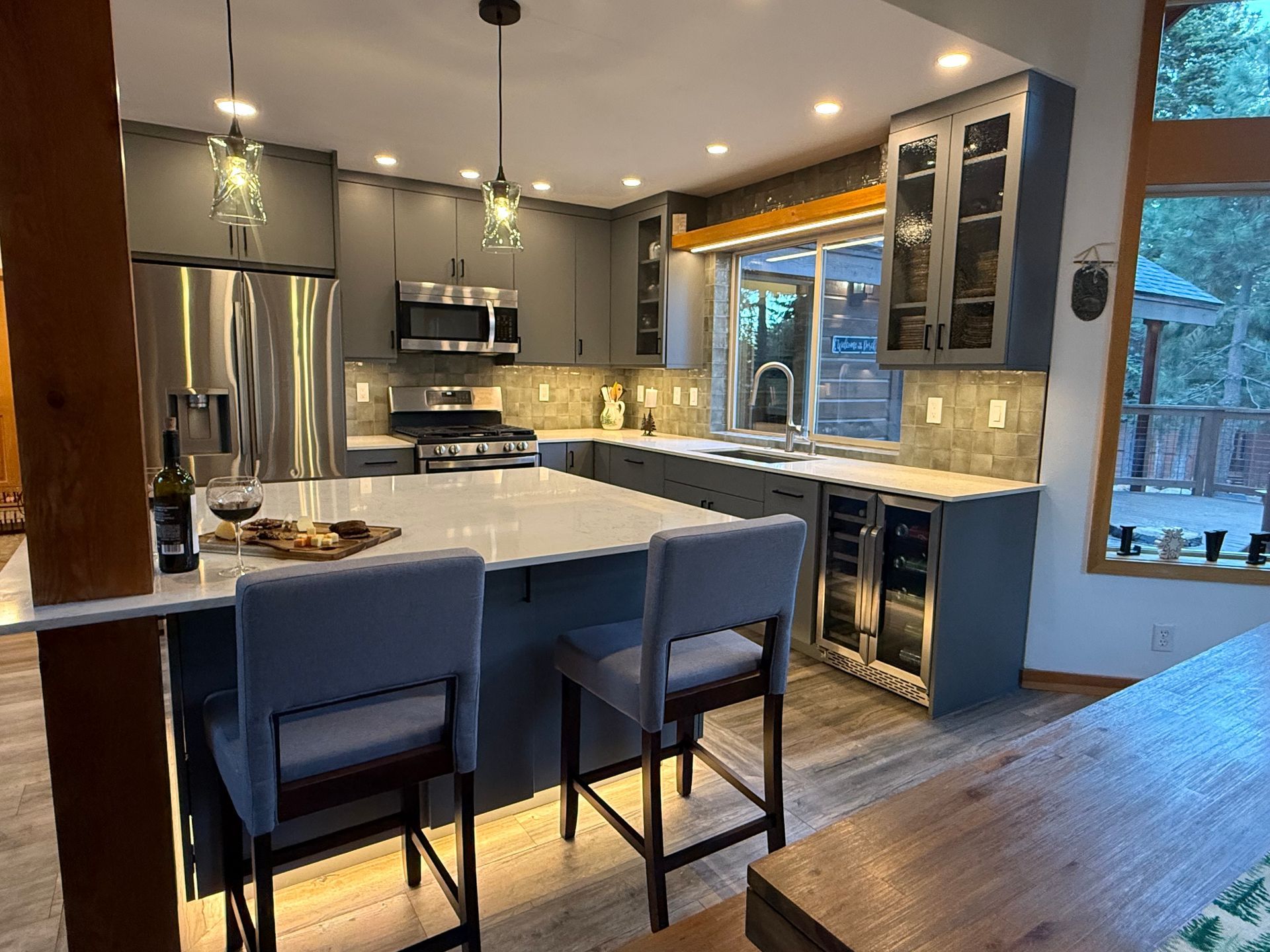 A kitchen with a large island , stools and a refrigerator.