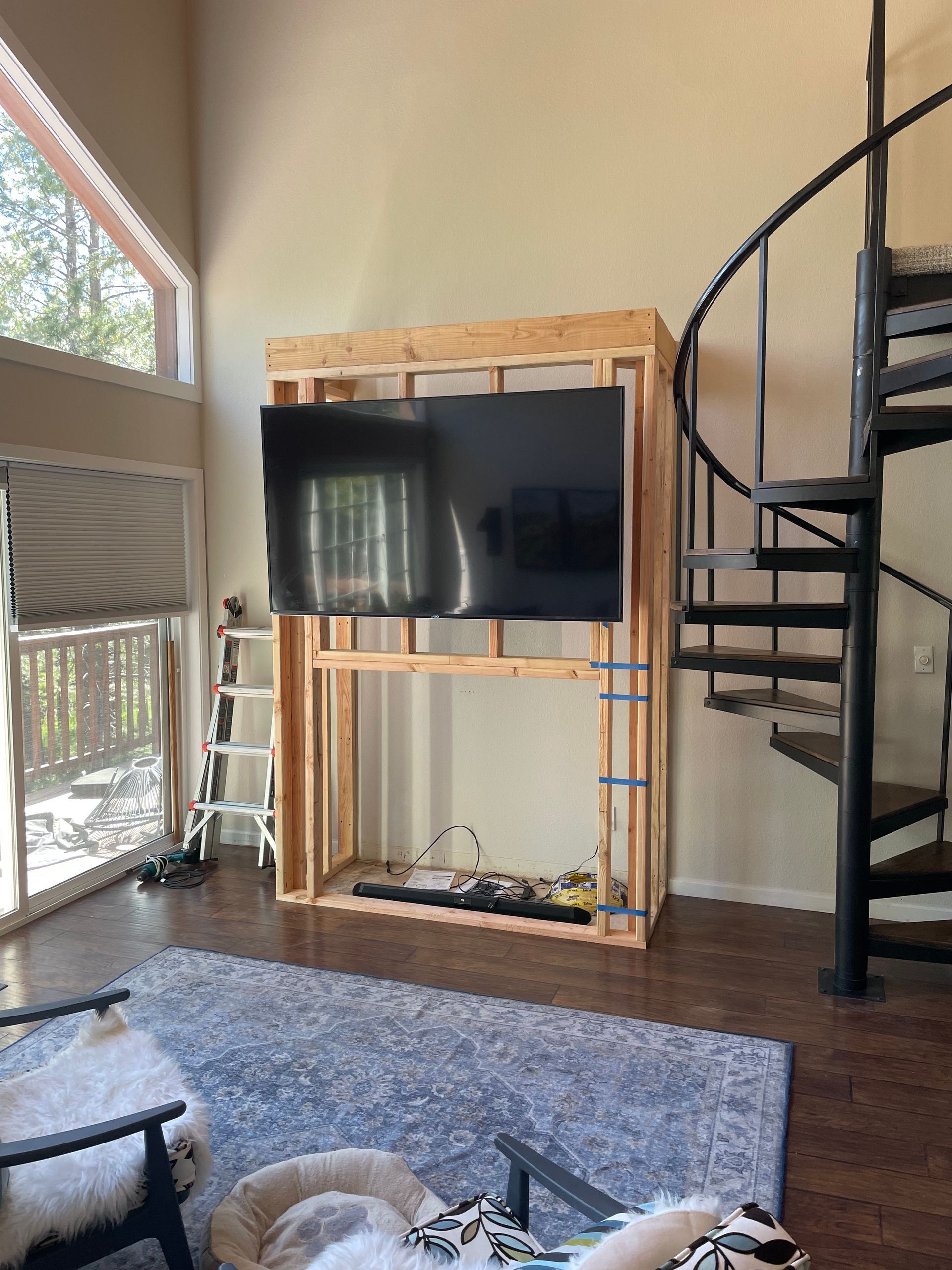A living room with a spiral staircase and a tv mounted on the wall.